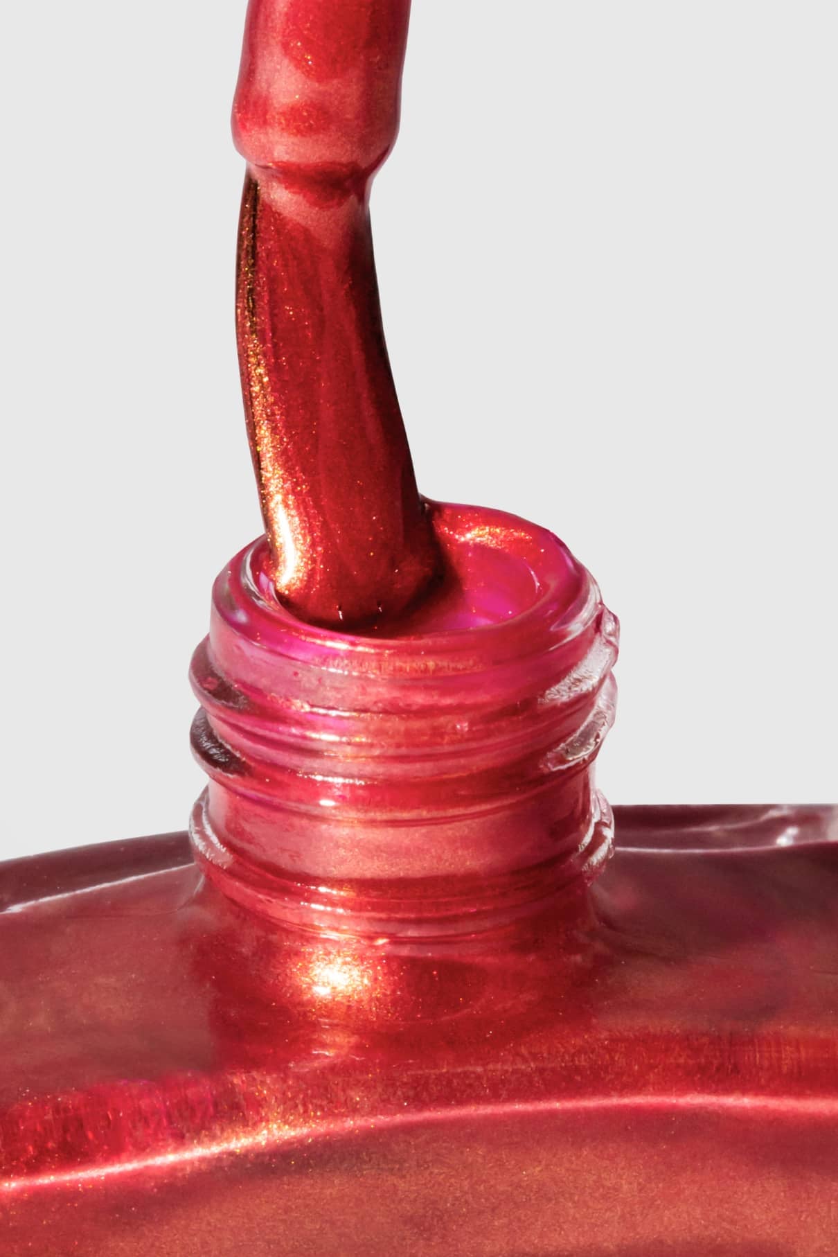 Nahaufnahme eines Pinsels, der in eine Flasche mit gitti no. 301 shimmery leuchtender Rotton Nagellack getaucht ist, wobei der Flaschenhals sichtbar ist.