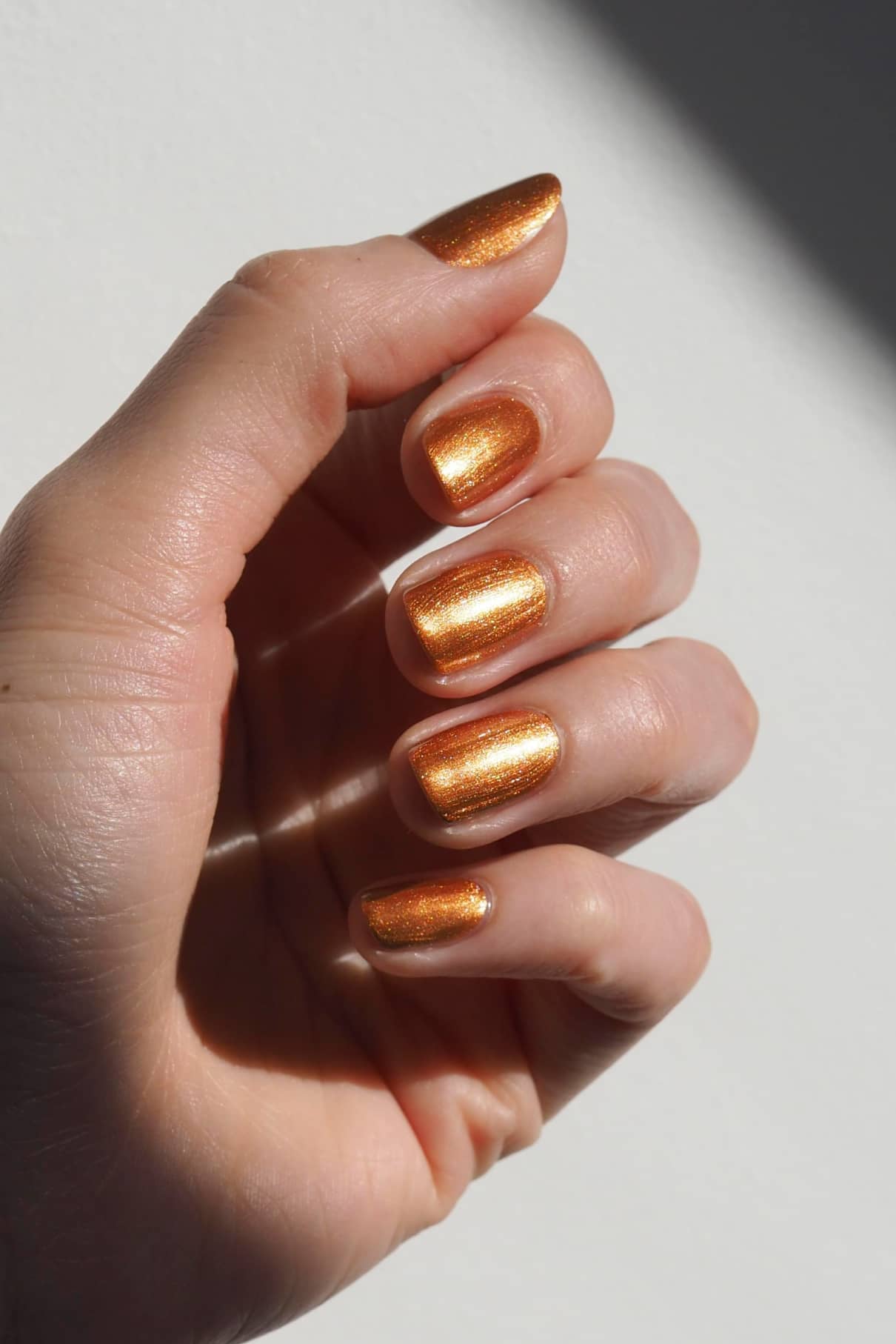 Eine Hand mit sauber manikürten Nägeln, lackiert mit schimmerndem gitti no. 302 Nagellack lackiert sind, vor einem schlichten weißen Hintergrund.
