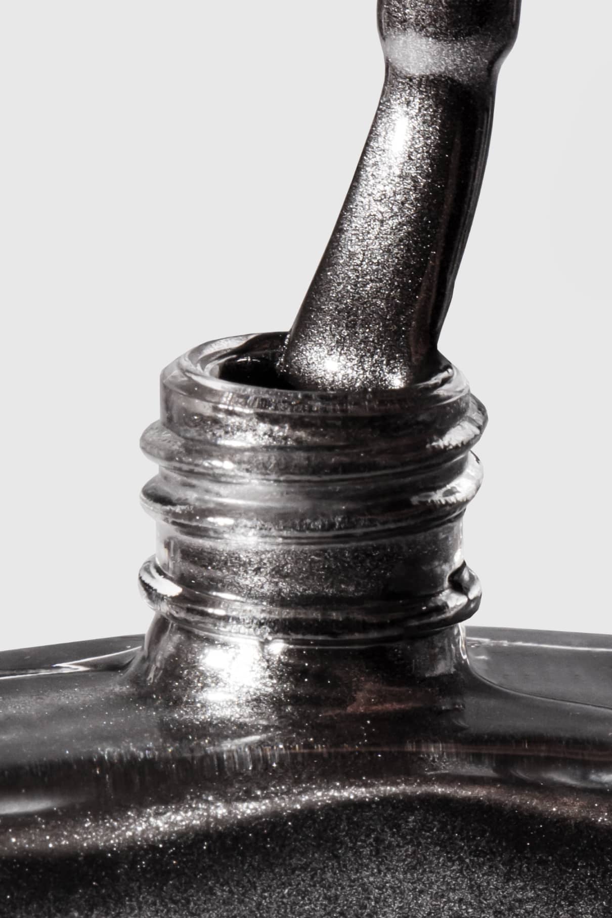 Eine Nahaufnahme eines Nagellackpinsels, der in eine Flasche gitti no. 303 getaucht ist, wobei der schwarze Farbton mit silbrigem Metallic-Finish vor einem schlichten Hintergrund zu sehen ist.