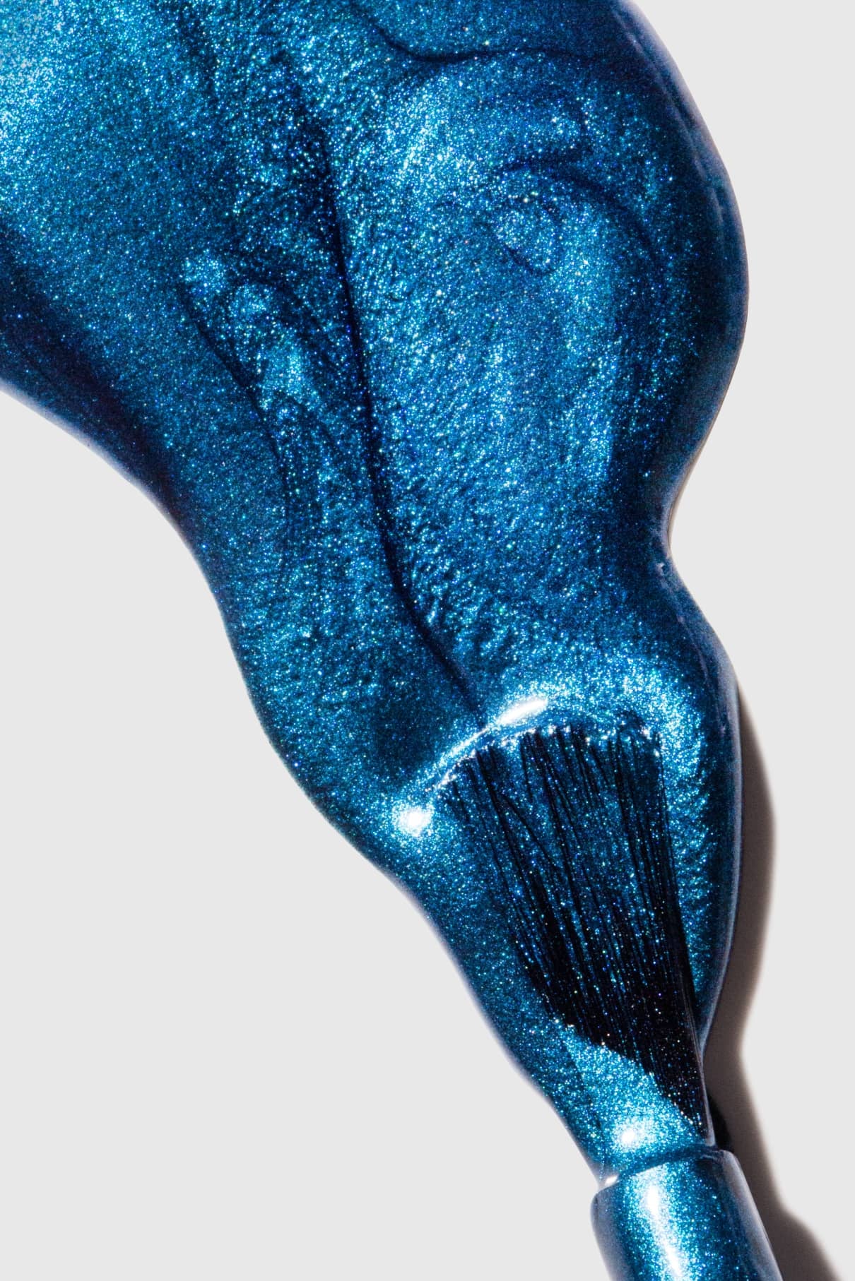 Nahaufnahme eines Pinsels, der gitti no. 304, ein schimmernder Metallic-Blau-Nagellack, in einer glänzenden, dicken Schicht auf einer weißen Oberfläche.