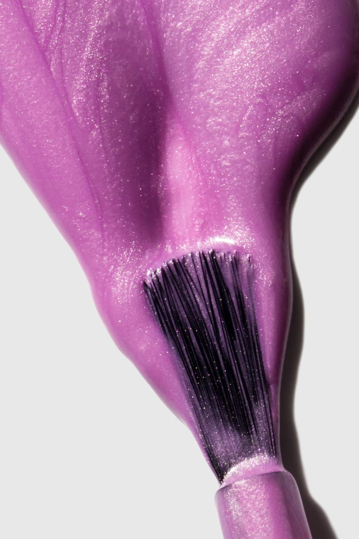 Nahaufnahme eines Pinsels, mit dem gitti no. 306 Nagellack - ein glänzender, pastellfarbener Lila-Ton mit Metallic-Mauve-Finish und dezenten violetten Untertönen - auf eine glatte Oberfläche auf.