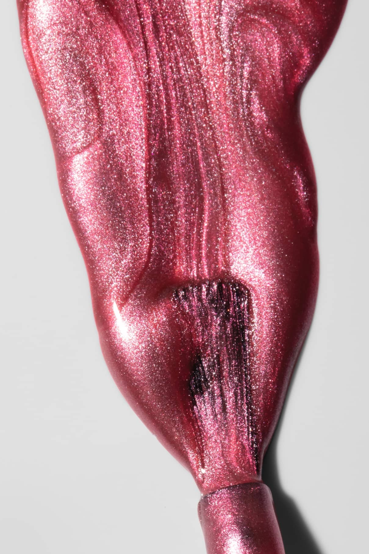 Gitti no. 309, ein rosafarbener Metallic-Nagellack, wird auf eine weiße Oberfläche gebürstet und enthüllt ein glänzendes, strukturiertes Finish in lebhaftem rötlichem Pink.