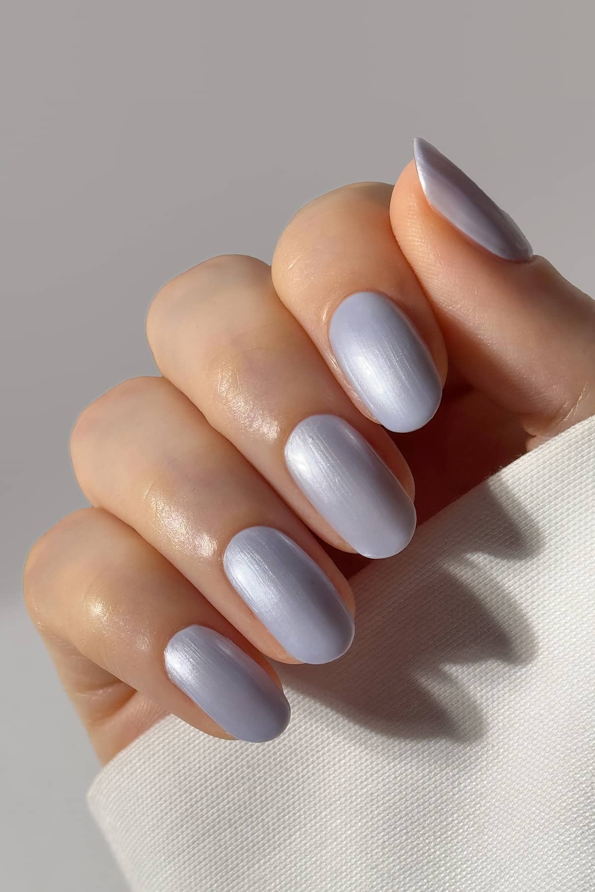 Eine Hand mit sauber manikürten Nägeln, lackiert in gitti no. 311, einem hellen, kühlen blau-lila Farbton mit dezentem Metallic-Finish, vor einem neutralen Hintergrund.