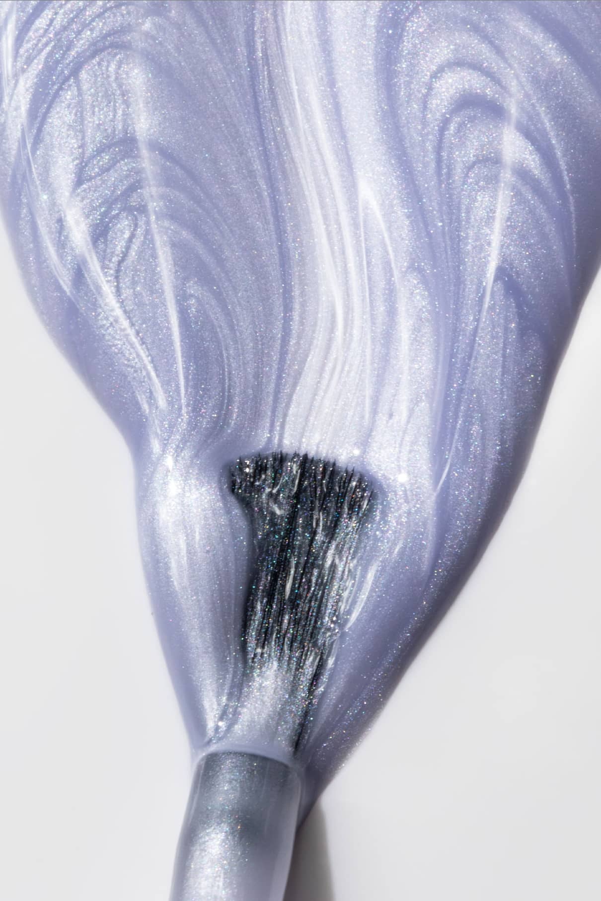 Nahaufnahme eines Pinsels, der gitti no. 311 Nagellack mit schimmerndem Metallic-Finish in sanften, wirbelnden Strichen auf eine weiße Fläche auf.