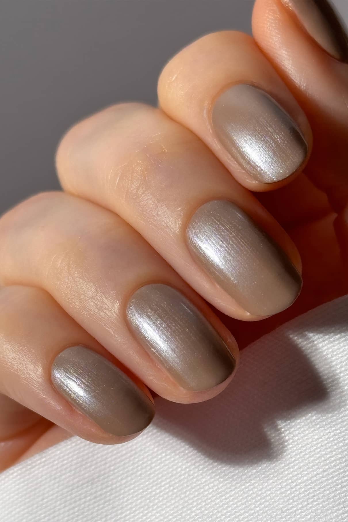 Nahaufnahme einer Hand mit sauber manikürten Nägeln in Metallic-Taupe, mit schimmerndem Finish und glänzendem plantPRO Glaze Top Coat.