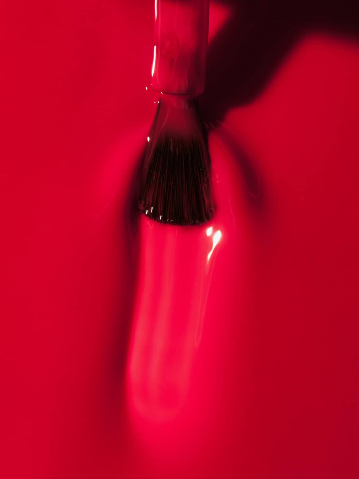 Nahaufnahme eines Nagellackpinsels, mit dem gitti no. 01+, ein intensiv glänzender roter Nagellack, auf eine glatte Oberfläche.