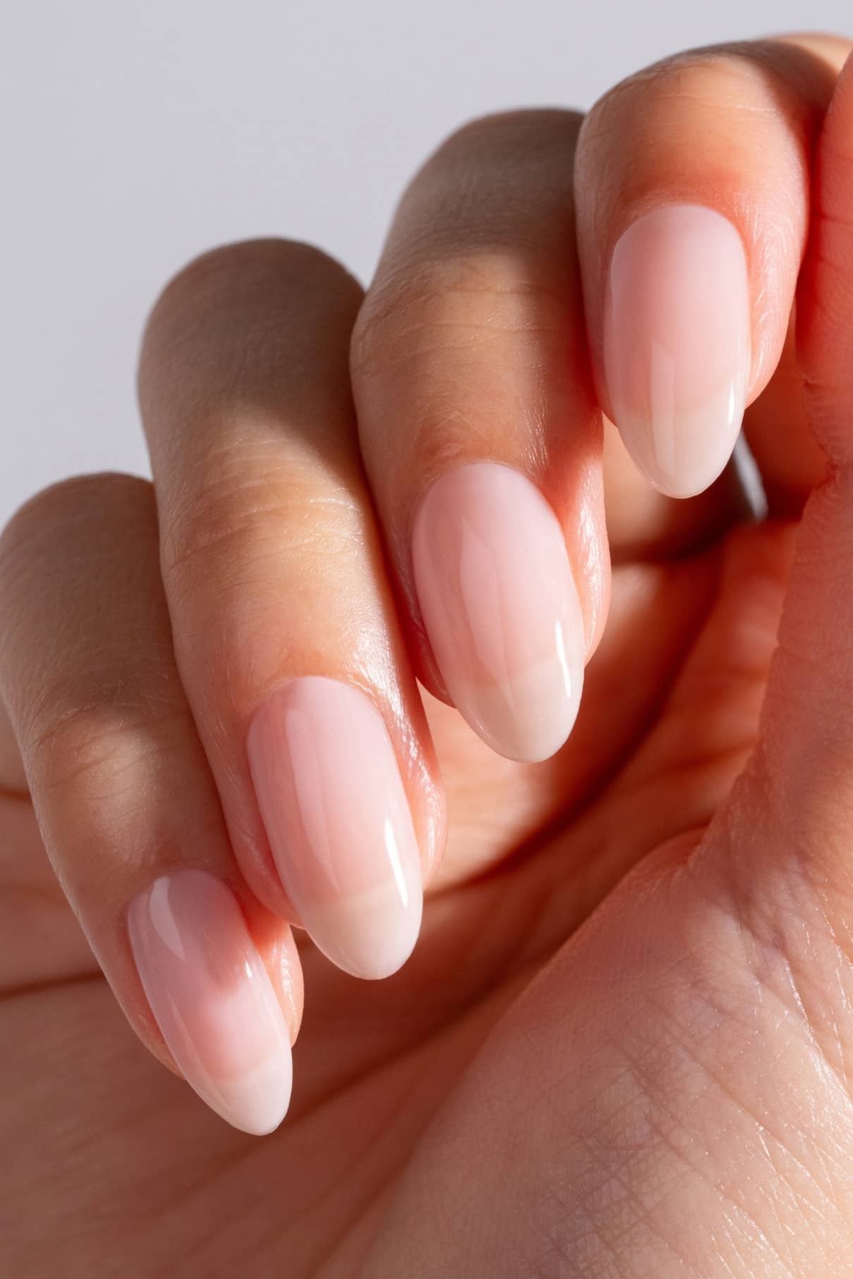 Eine Nahaufnahme einer Hand mit natürlichen, mandelförmigen Nägeln zeigt eine glänzende Maniküre in gitti no. 04+ für einen eleganten, frischen Look.