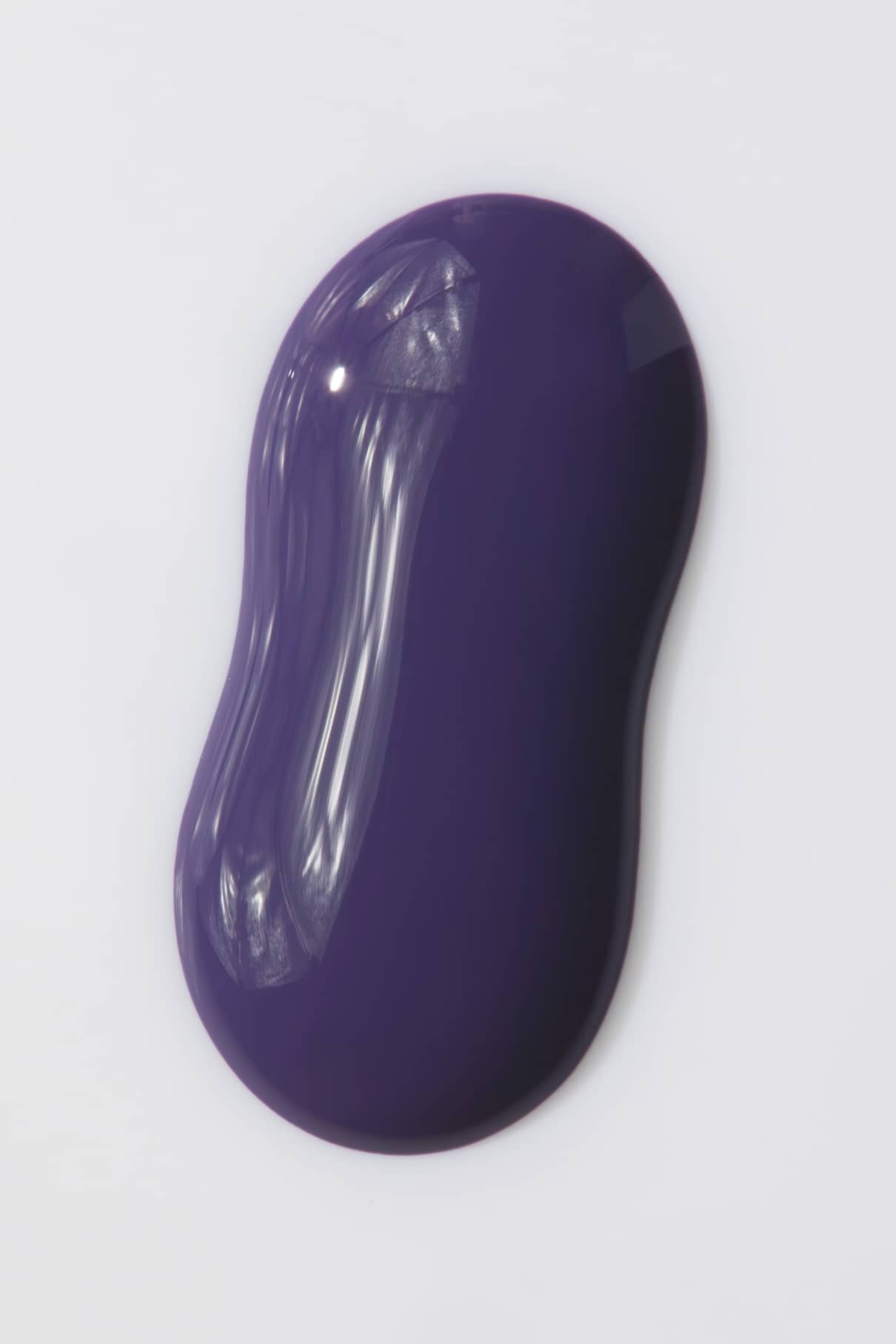 Ein glatter, glänzender Klecks von gitti no. 07+ mit einem dunkelvioletten Farbton mit lila Unterton und geschwungenen Rändern ruht auf einem schlichten weißen Hintergrund.