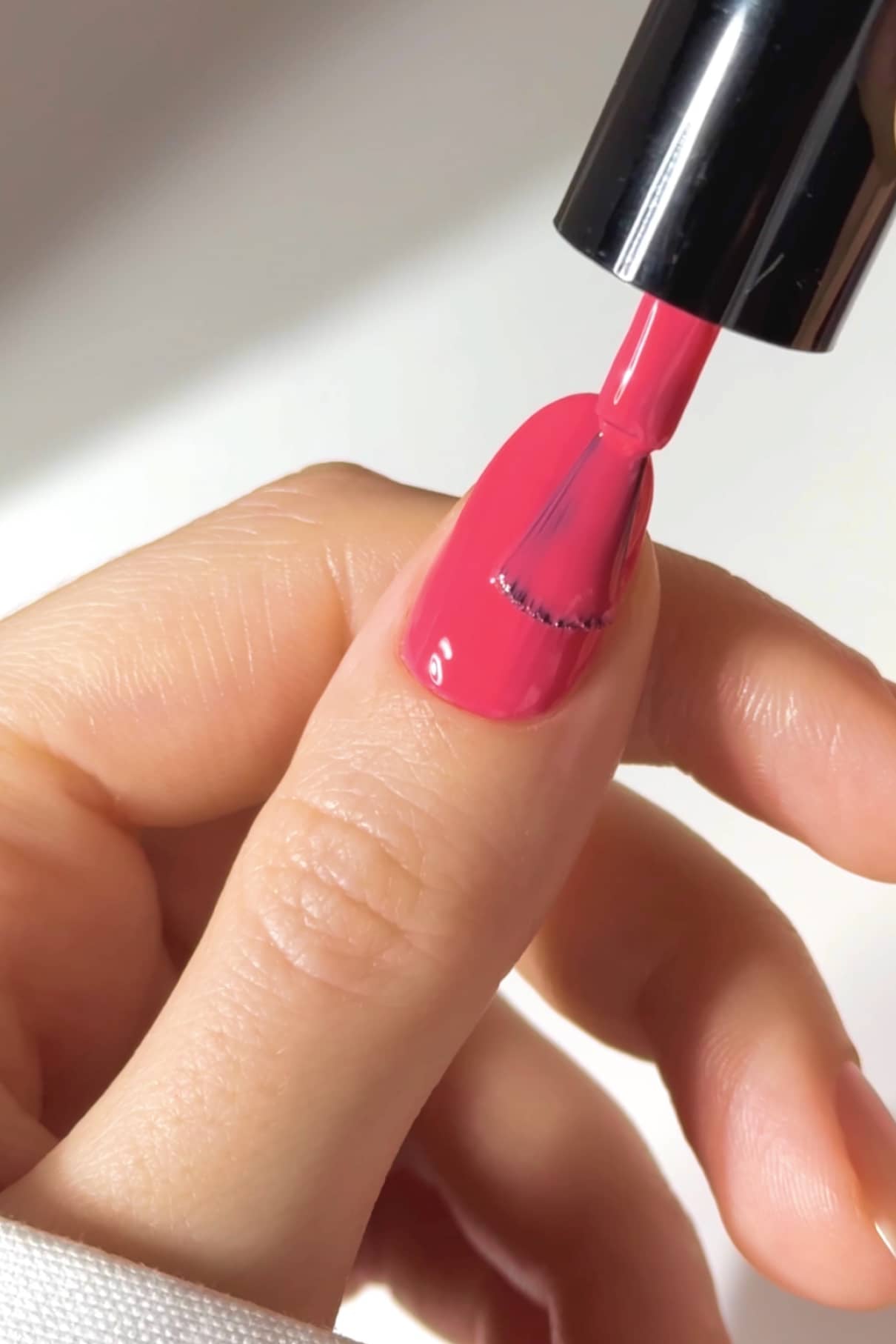 Auf einer Hand wird gitti no. 08+ Nagellack in strahlendem Pink mit einem Nagellackpinsel auf den Daumennagel aufgetragen.