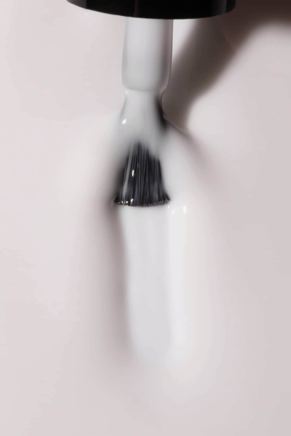 Nahaufnahme eines Nagellackpinsels, mit dem gitti no. 11+, ein milchig-weißer Farbton, auf eine glatte Oberfläche - perfekt für ein halbtransparentes Nageldesign.