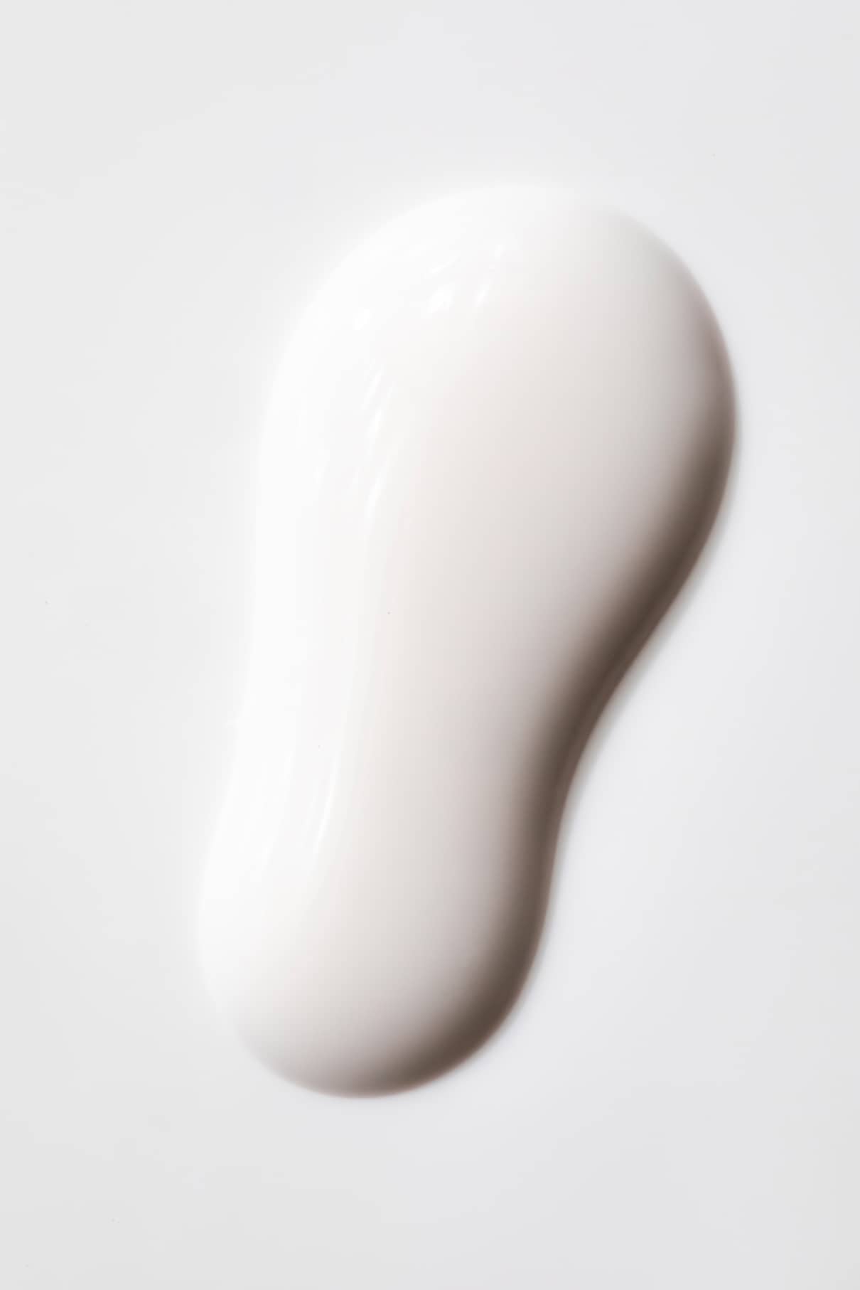 Eine weiße, glänzende Flüssigkeit mit glatten Rändern auf einer festen Oberfläche, die an milchiges Weiß erinnert - perfekt, um ein zartes Weiß oder halbtransparentes Nageldesign mit gitti no. zu inspirieren. 11+.