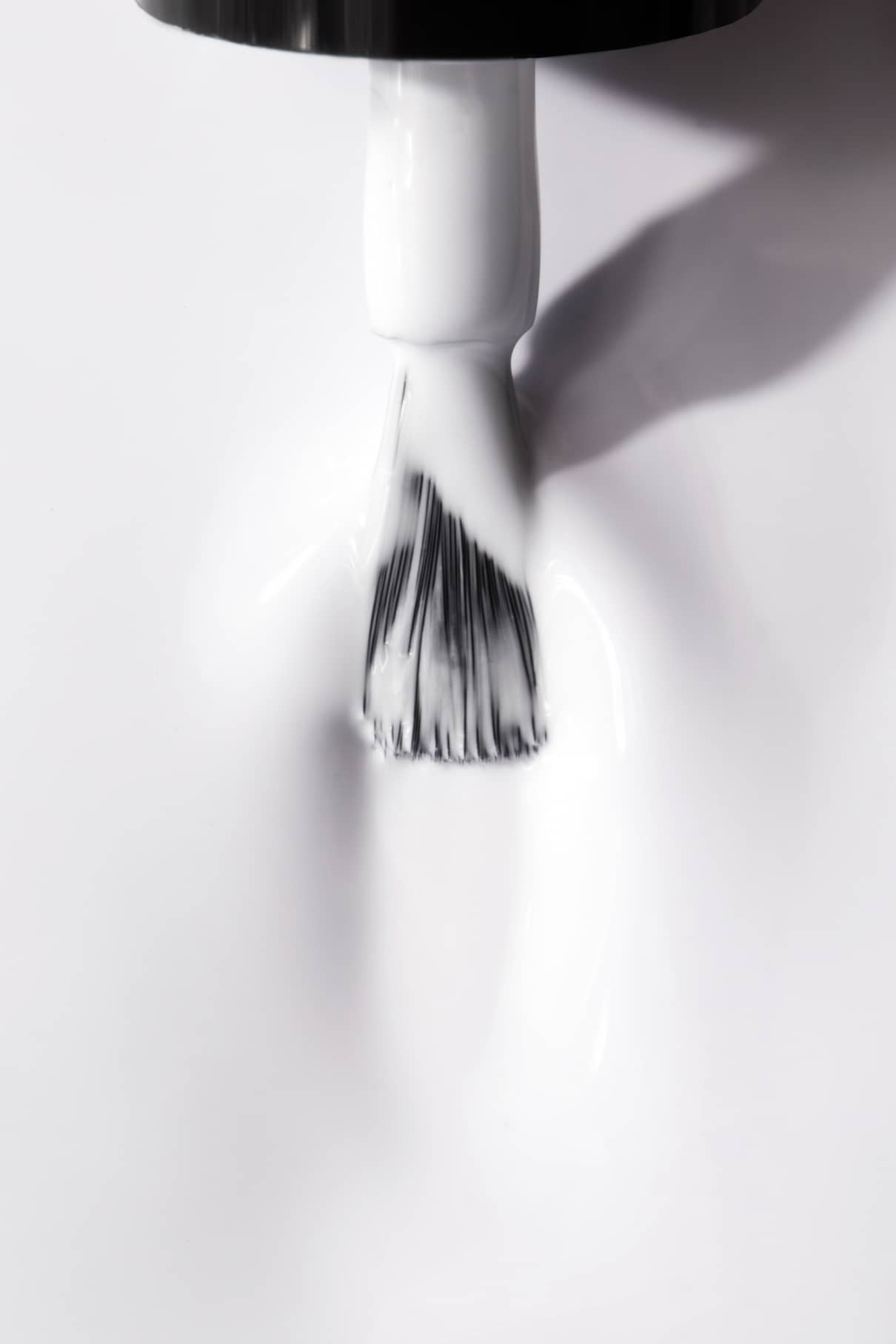 Nahaufnahme eines Pinsels, mit dem eine Schicht des Nagellacks gitti no. 13+ Nagellack auf eine glatte Oberfläche aufträgt.