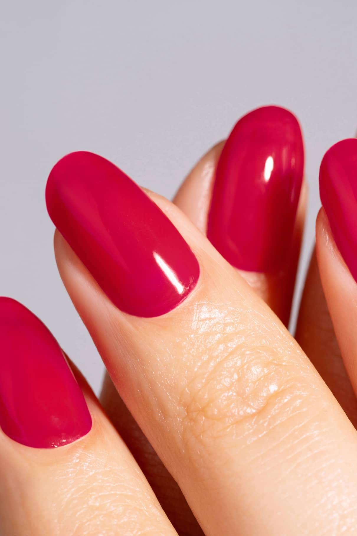 Nahaufnahme von drei Fingern mit glatten, glänzenden Nägeln in der intensiven rosa Farbe von gitti no. 16+ auf sauber manikürten Nägeln vor einem neutralen Hintergrund.