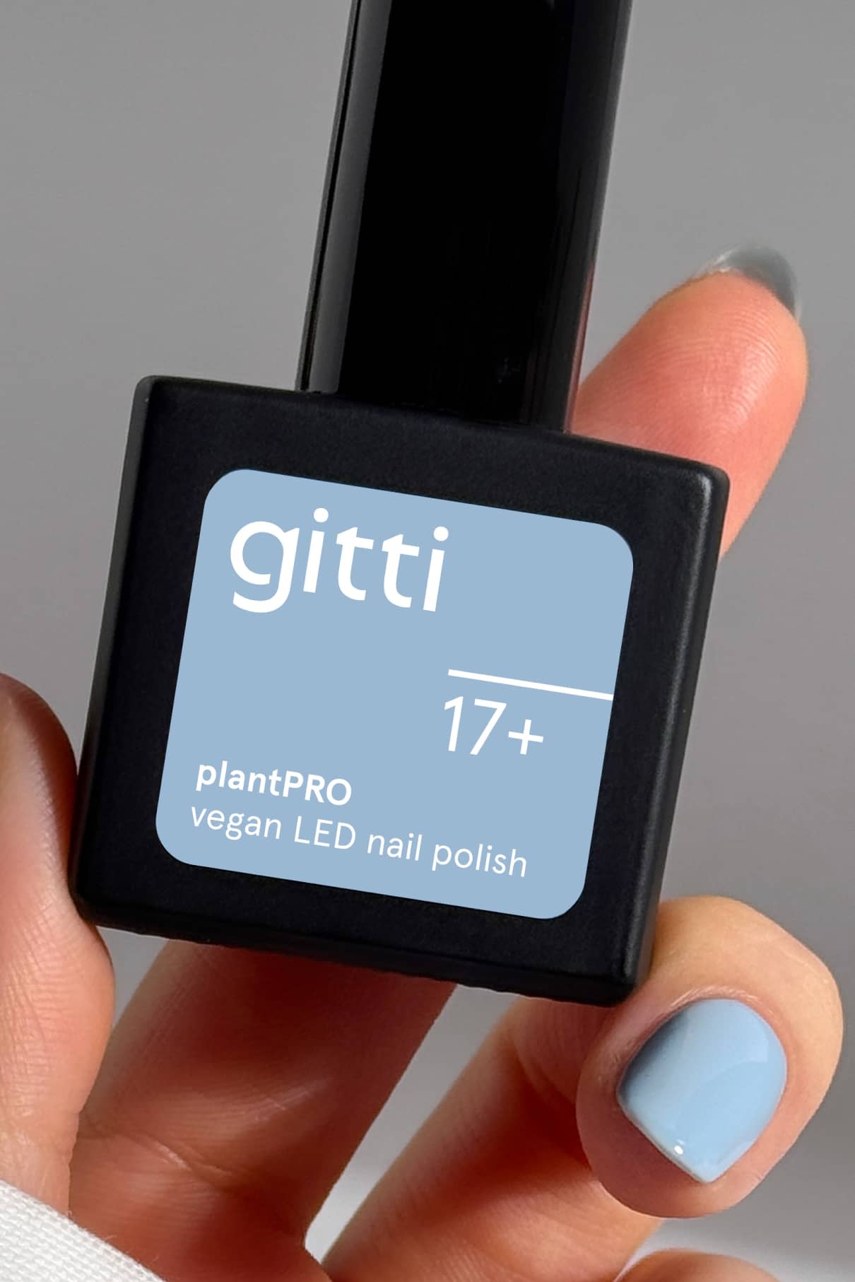 Eine Hand hält eine Flasche aus dem plantPRO System + Lampe; die Nägel sind hellblau lackiert, passend zum Etikett auf der veganen LED-Nagellackflasche.