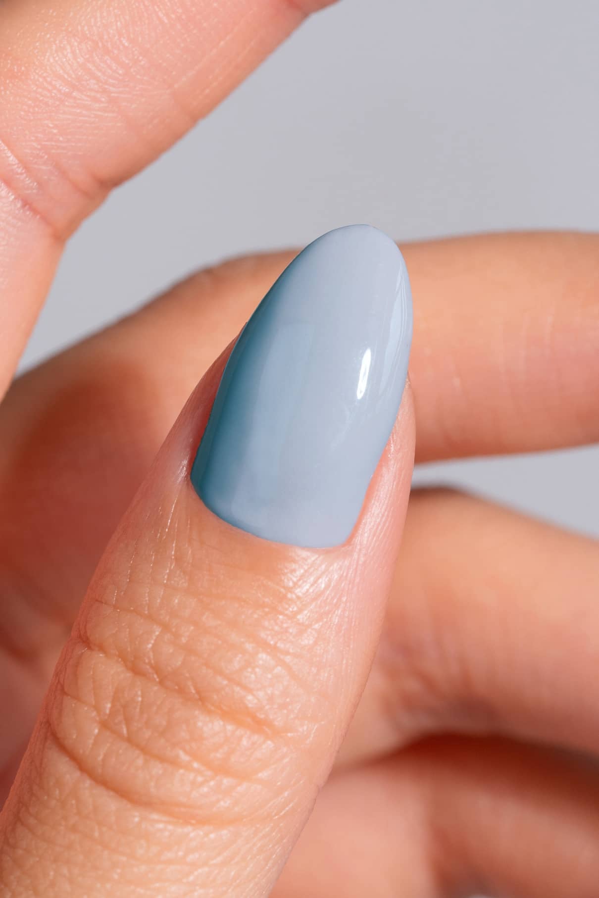 Nahaufnahme einer Hand mit Daumen mit glattem, glänzendem Nagellack in frischem Hellblau, mit gitti no. 17+.