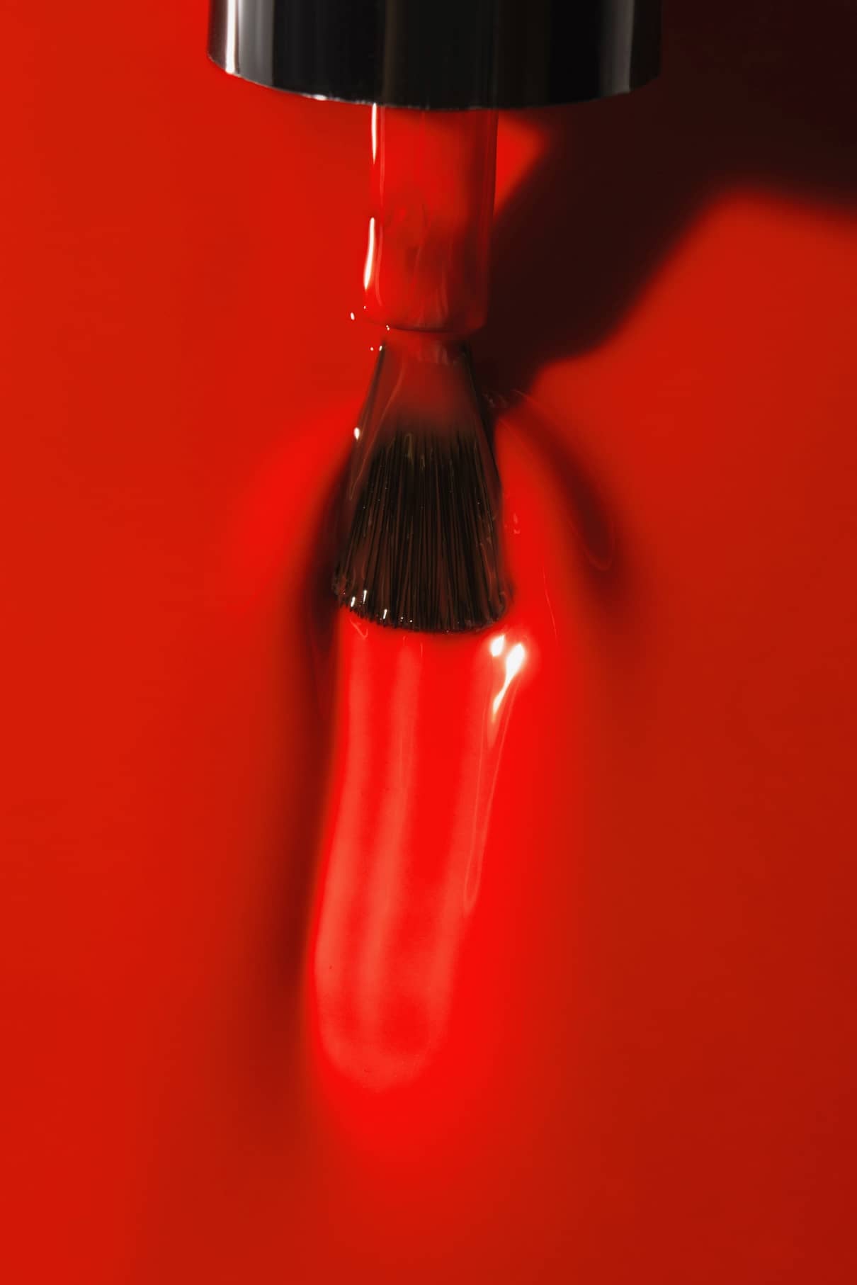 Nahaufnahme eines Pinsels, der den glänzenden, intensiven gitti no. 18+ Orange-Rot-Nagellack auf eine glatte Oberfläche aufzutragen, wobei das nasse und reflektierende Finish deutlich sichtbar ist.