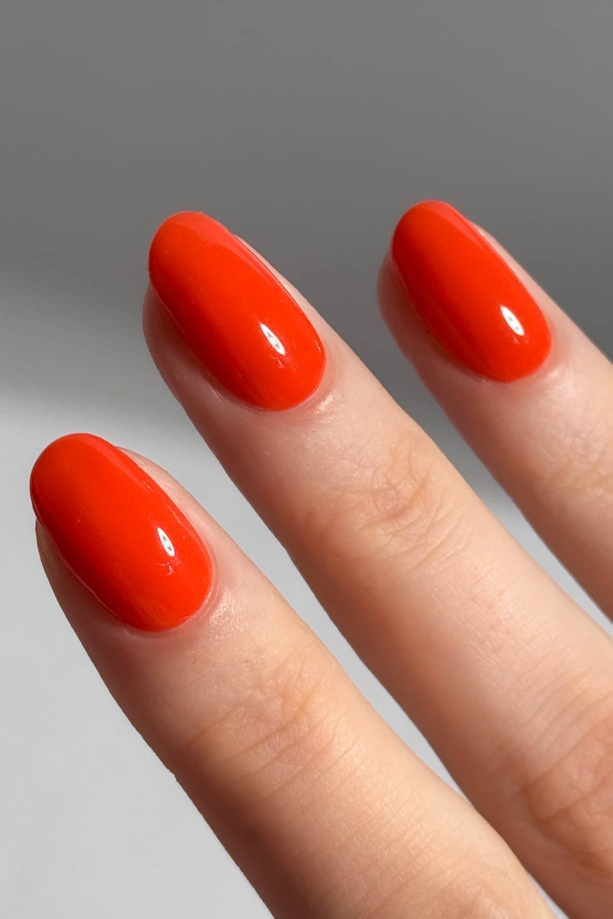 Nahaufnahme von drei Fingern mit sauber manikürten Nägeln, die in gitti no. 18+, einem intensiven Orangerot mit einem glänzenden, lebendigen Finish.