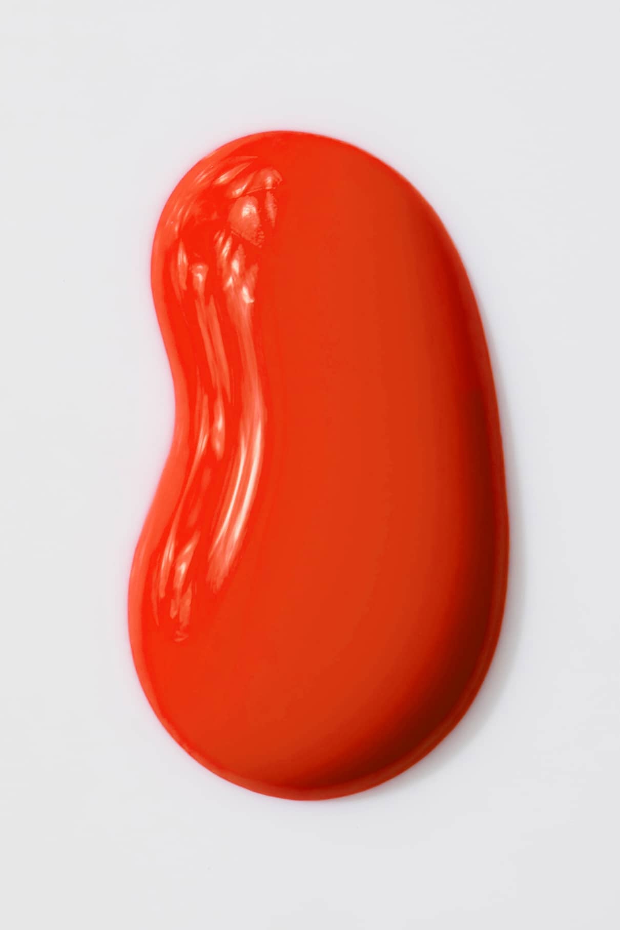 Ein glatter, glänzender Abstrich von gitti no. 18+ hebt sich in seinem intensiven Orange-Rot-Ton lebhaft vom weißen Hintergrund ab.