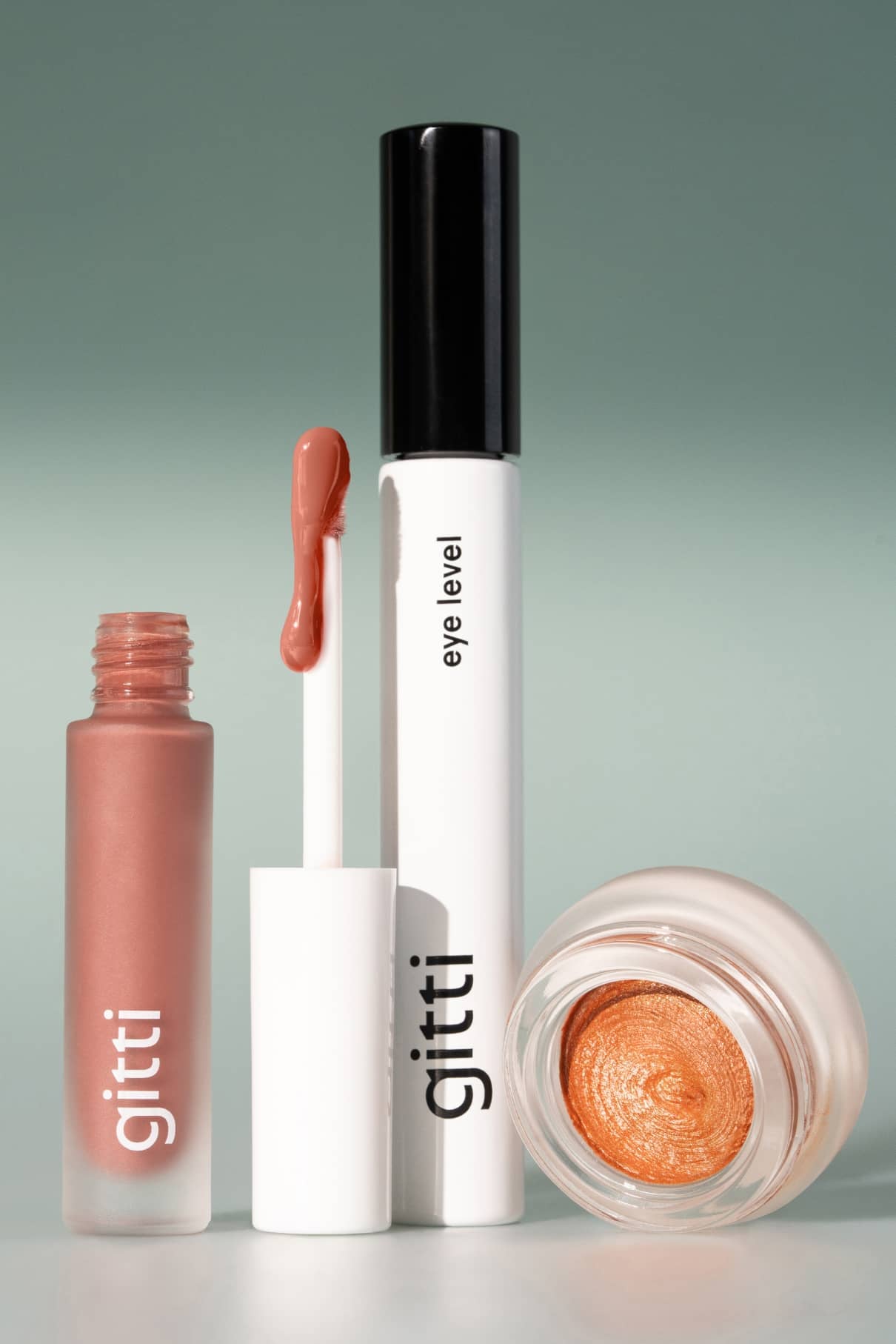 Das Lash, Lip & Cheek Trio besteht aus einem gitti liquid Lip Glaze mit Applikator, einer gitti eye level Mascara und einem offenen Tiegel mit schimmerndem Bronze-Cremelidschatten.
