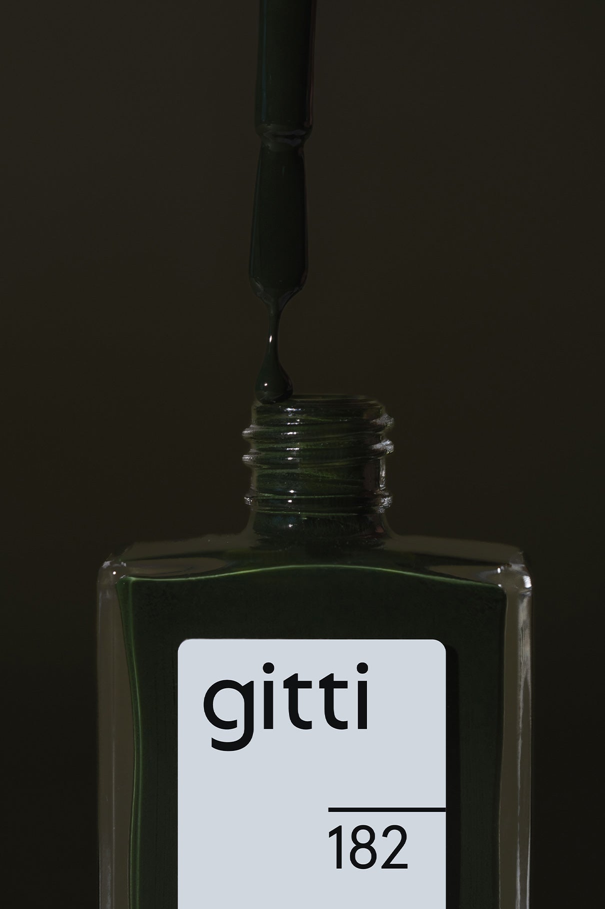 Eine Flasche gitti no. 182 Nagellack mit einem Pinselapplikator, der dunklen Tannengrün-Lack in die offene Flasche tropft.