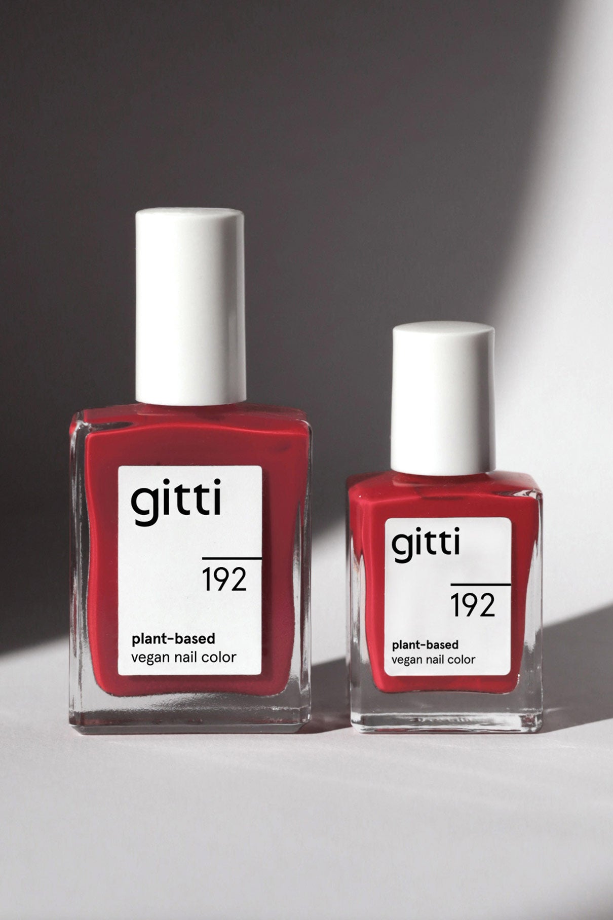 Zwei Fläschchen aus dem Mini Getaway Set mit der pflanzlichen veganen Nagelfarbe Gitti in der Farbe 192 stehen nebeneinander auf einer hellen Fläche, die von natürlichem Licht beleuchtet wird - perfekt für Ihre nächste Reise.