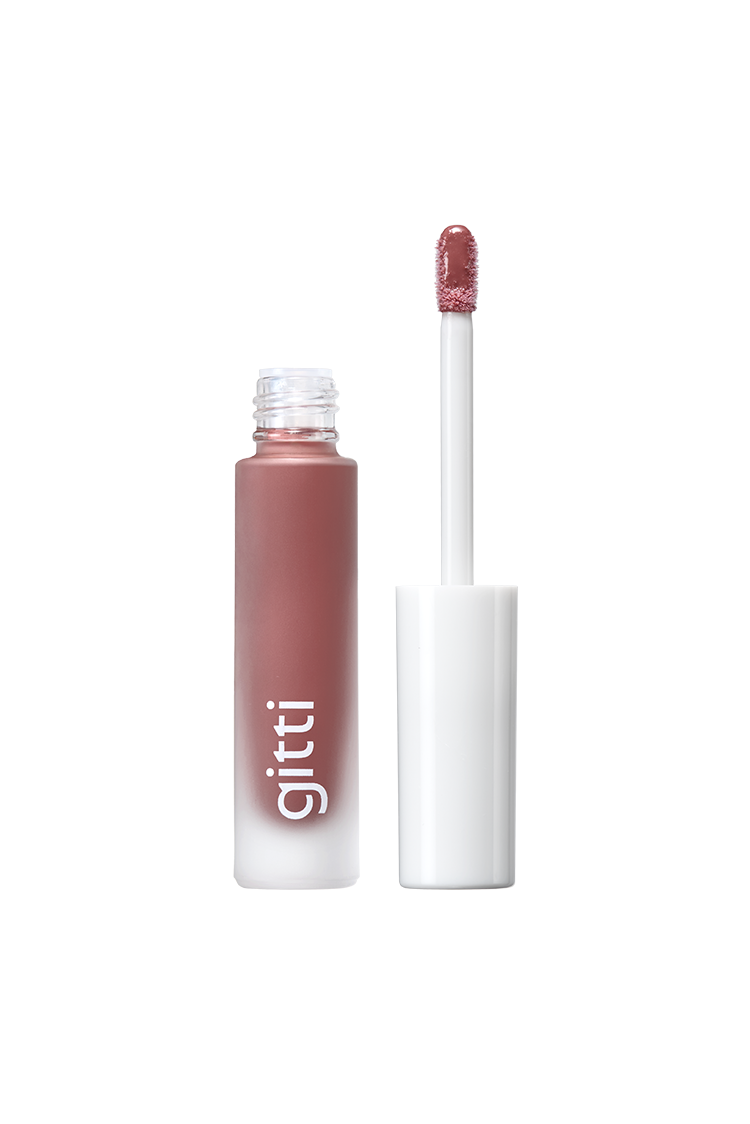 Lip Glaze no. 01 ist ein matter, lilafarbener, flüssiger Lippenstift mit weißer Kappe und Applikator mit der Aufschrift "gitti", der einen einzigartigen Gloss Hybrid-Effekt für Fans des hochglänzenden Finish-Looks bietet.