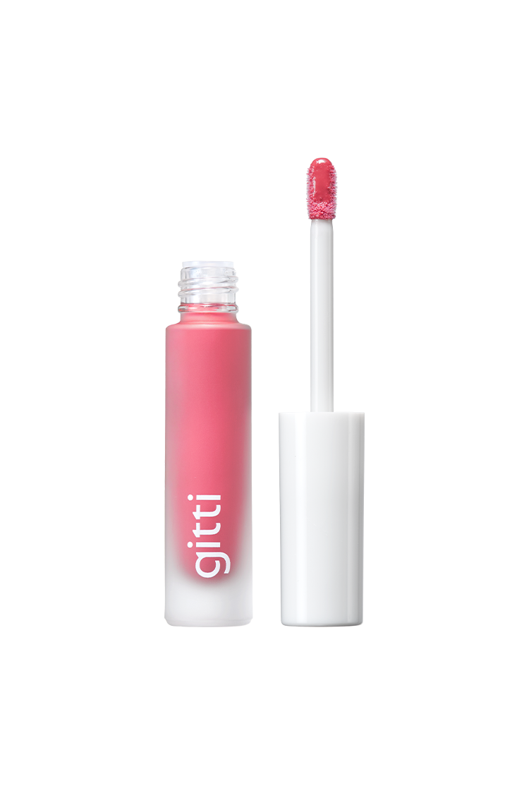 Eine Tube Lip Glaze no. 03 rosa flüssiger Lippenstift mit einer weißen Kappe und Applikator mit der Aufschrift gitti. Die Gloss Hybrid Formel gibt ein hochglänzendes Finish. Der Applikator steht aufrecht neben der offenen Tube.