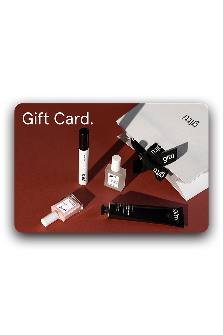Ein Digitaler Geschenkgutschein und vier minimalistische Kosmetikprodukte sind auf einer dunkelroten Fläche neben einer weißen Geschenkbox mit schwarzer Schleife angeordnet.