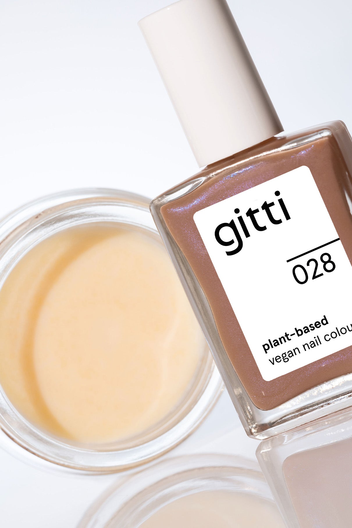 Das Express Colour & Remove Kit mit pflanzenbasiertem veganem Nagellack steht neben einem offenen Cremebehälter auf einer reflektierenden weißen Oberfläche und präsentiert innovative pflanzenbasierte Farben für eine saubere Beauty-Routine.