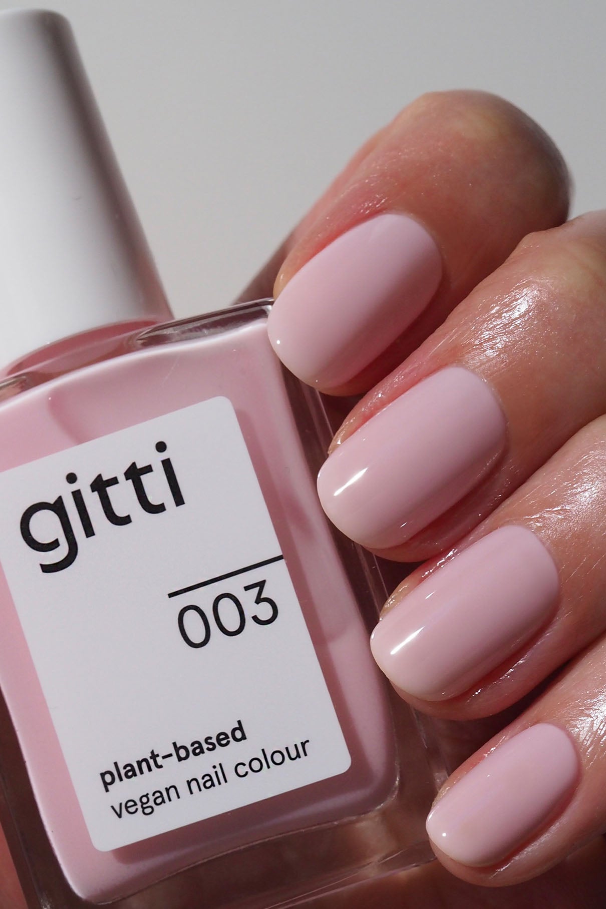 Eine Hand mit sauber manikürten hellrosa Nägeln hält Gitti's Plant Duo + Remover mit pflanzlicher, veganer Nagelfarbe und Unter- und Überlack für ein makelloses, lang anhaltendes Finish.