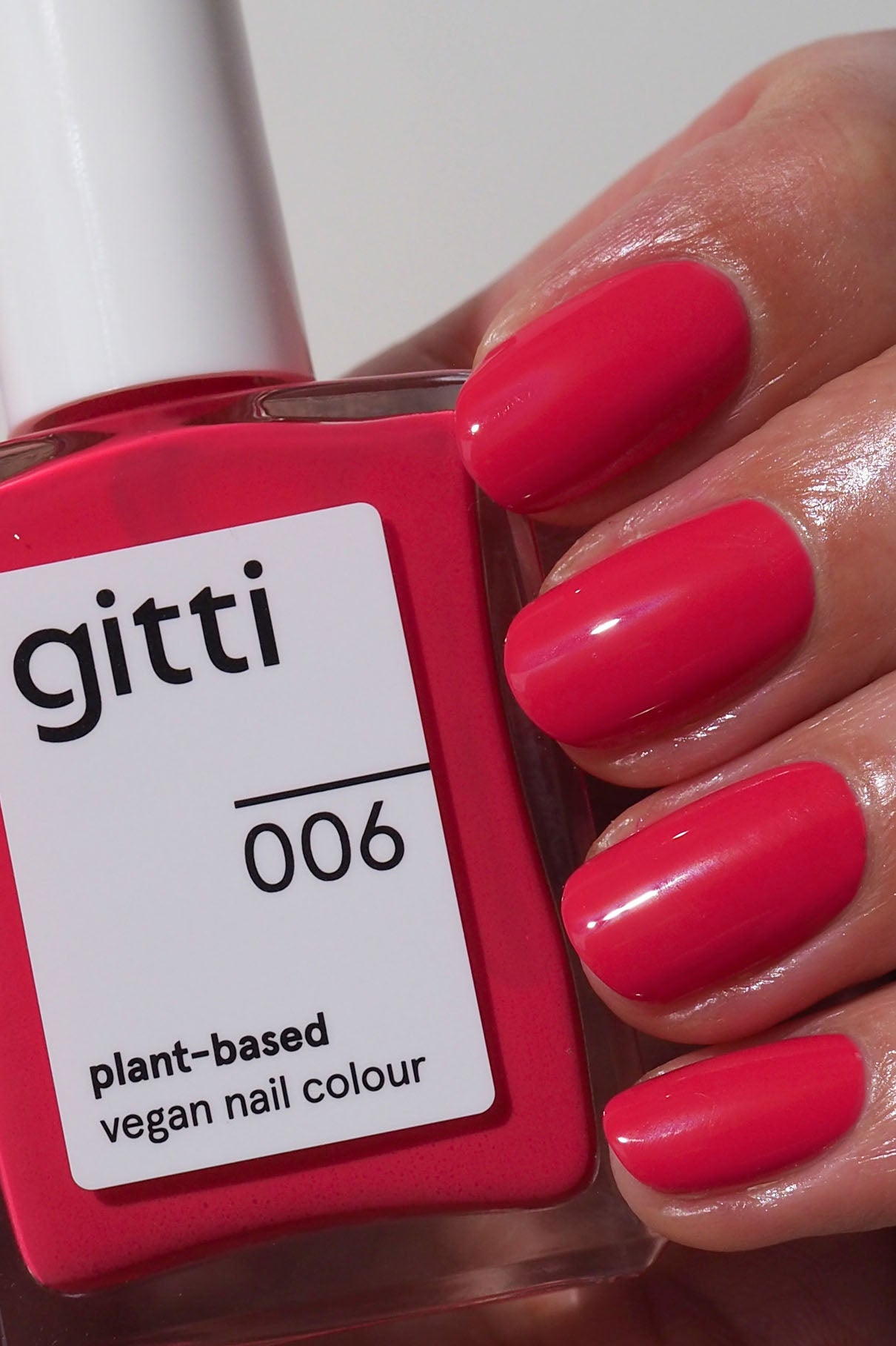 Eine Hand mit kurzen, sauber manikürten Nägeln, die leuchtend rosa lackiert sind, hält eine Flasche aus dem Express-All-in-One-Set, das mit einem Hochglanz-Topcoat für zusätzlichen Glanz versehen ist.