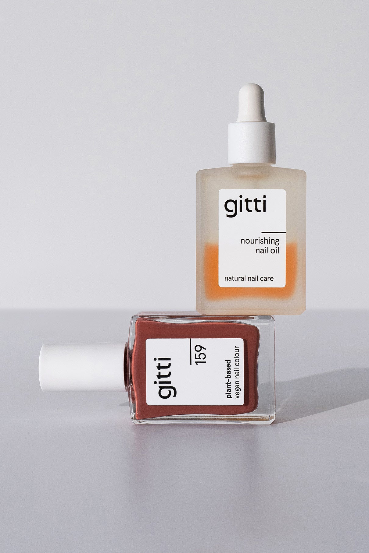 Das Minimalist Manicure Set enthält zwei Glasflaschen mit der Aufschrift gitti: eine mit pflegendem Nail Care Produkt-Öl und eine mit veganer Nagelfarbe in der Farbe 159, die beide auf einer weißen Fläche stehen.