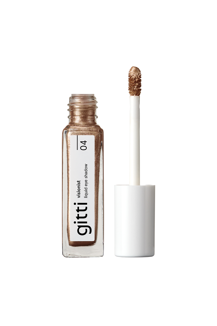 Eine Tube des flüssigen Lidschattens Visionist Nr. 04 in Sienna Glow steht mit dem Applikatorstab aufrecht neben der geöffneten Flasche - ein lang anhaltender Lidschatten in warmem Gold.