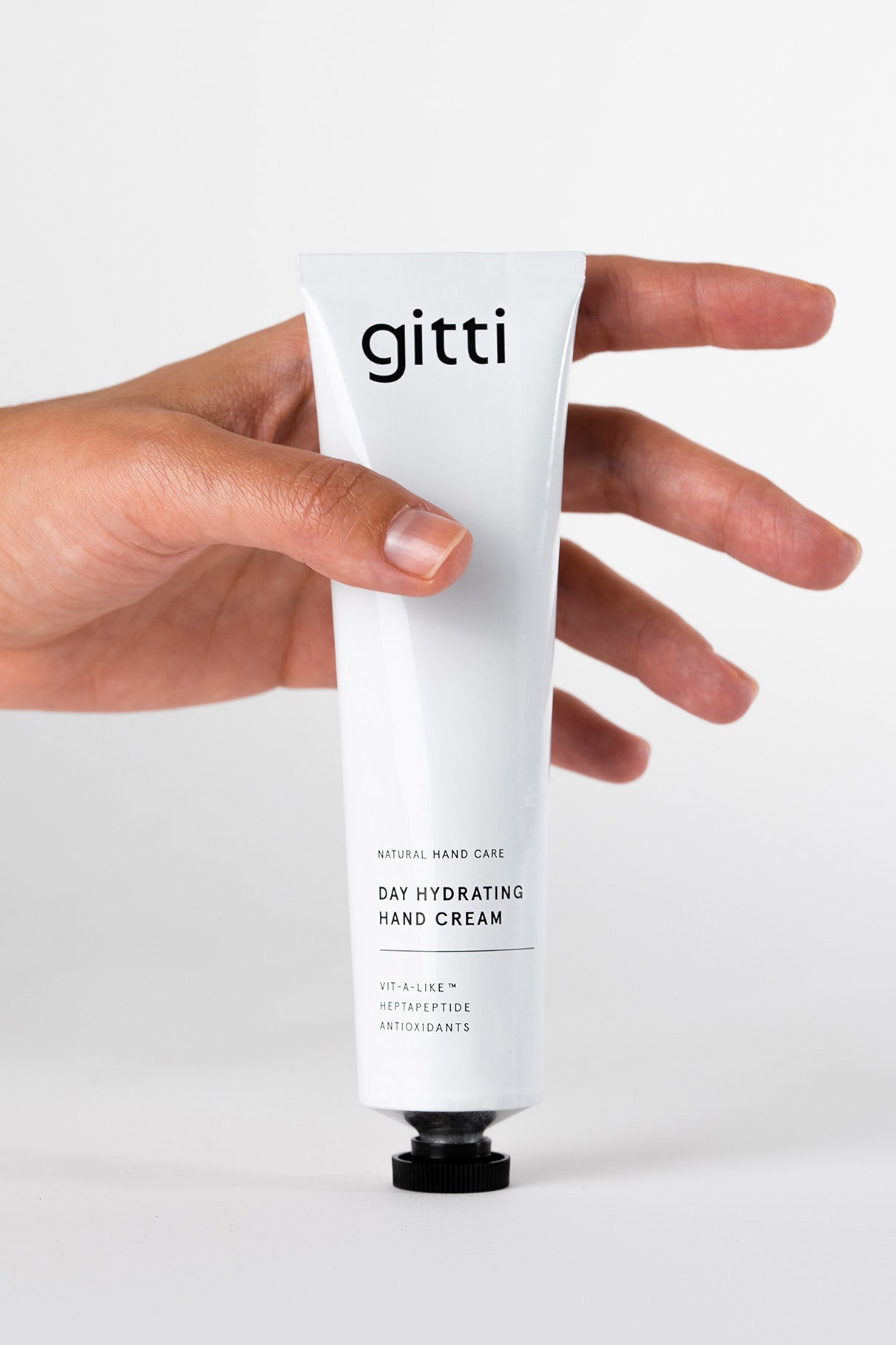 Eine Hand hält eine Tube der Day Hydrating Hand Cream, ideal für die tägliche Handpflege, vor einem schlichten weißen Hintergrund.
