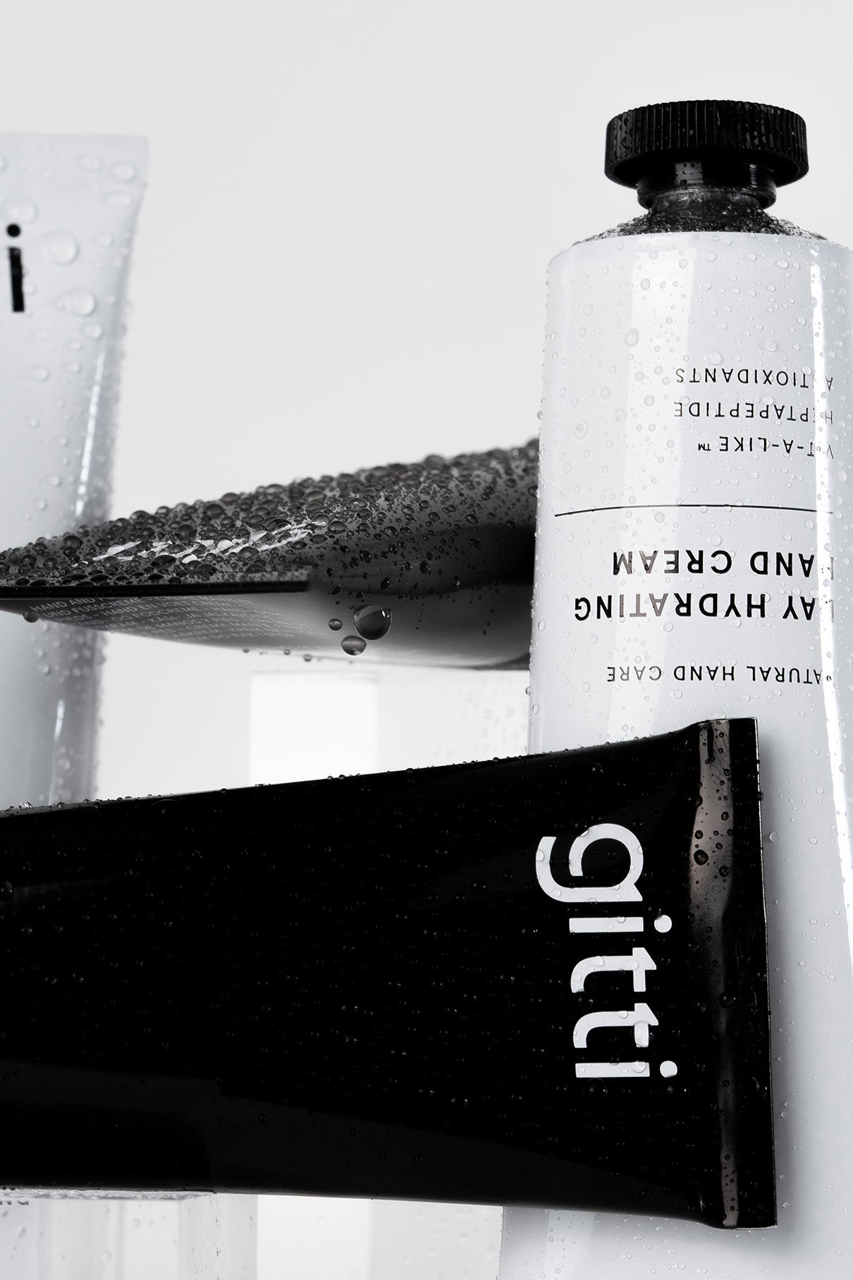 Nahaufnahme des Silky Hands Duo: eine schwarze gitti Handpeeling-Tube und eine weiße feuchtigkeitsspendende Handcreme, beide mit Wassertropfen - ein belebendes Set für Ihre tägliche Handpflege.