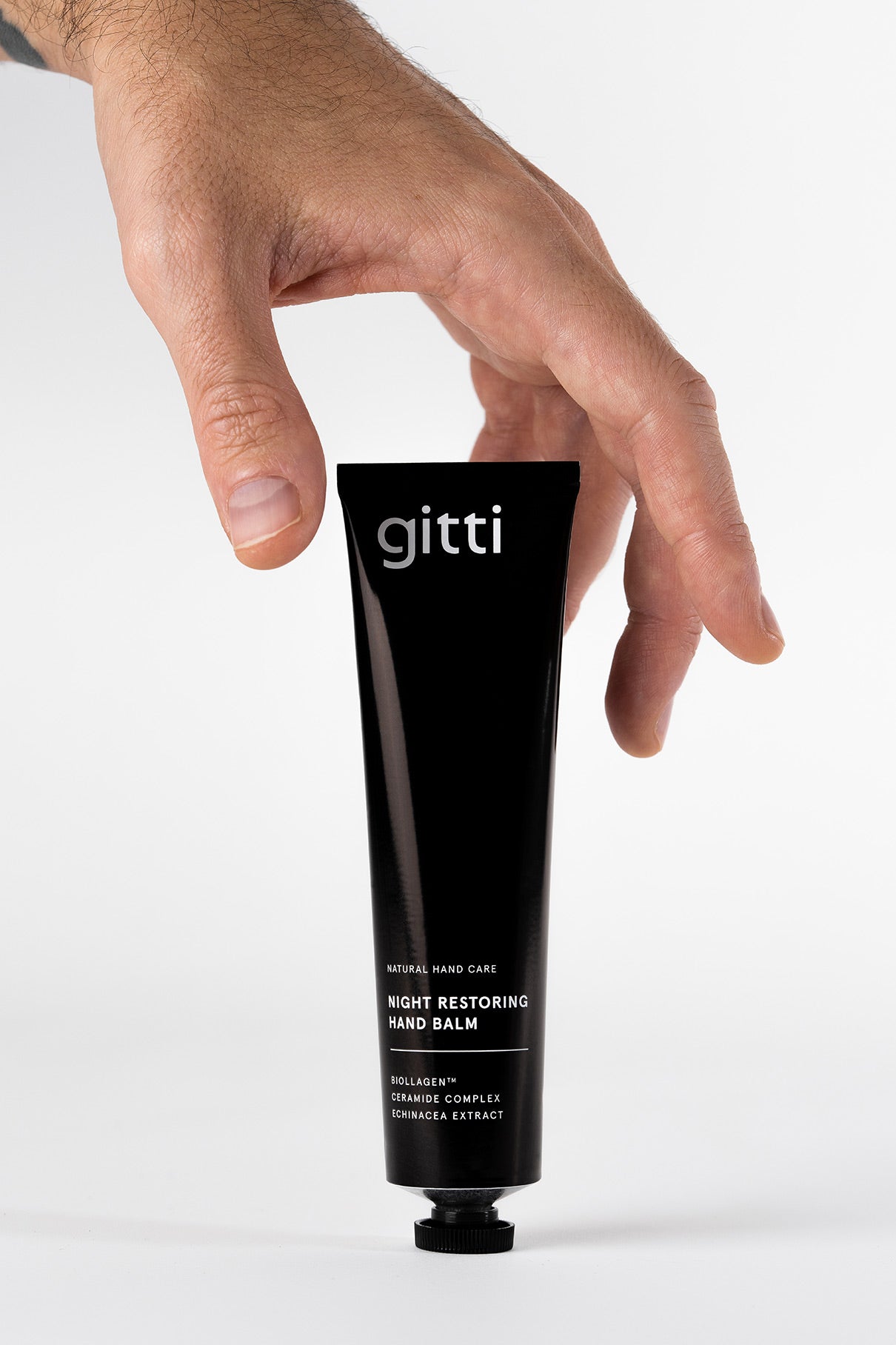 Eine Hand streckt sich nach einer schwarzen Tube mit der Aufschrift Silky Hands Duo, auf der auf einem schlichten weißen Hintergrund passende Artikel abgebildet sind.