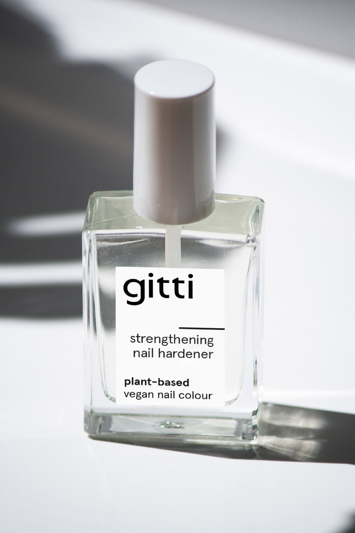 Eine klare Glasflasche mit einer weißen Kappe, die als pflanzlich und vegan gekennzeichnet ist, steht auf einer weißen Oberfläche - perfekt für stärkere Nägel und die Pflege brüchiger Nägel.