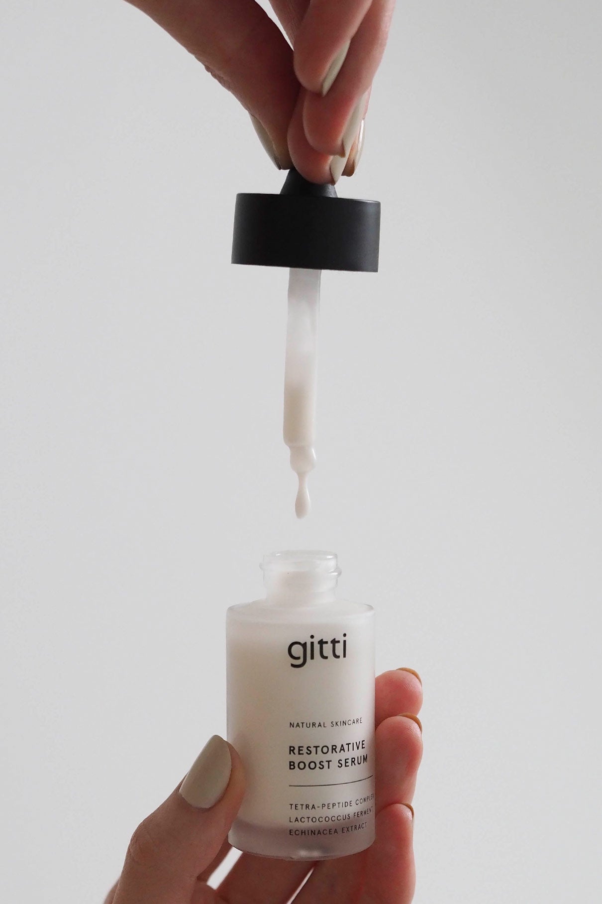 Eine Hand hält einen Tropfer über einer offenen Flasche mit der Aufschrift Restorative Boost Serum, in die ein Tropfen des Serums fällt - ideal, um die Feuchtigkeit und Elastizität der Haut zu erhöhen.