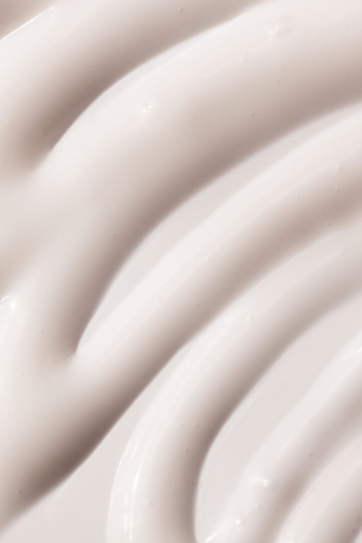 Nahaufnahme einer weißen, cremigen Substanz mit glatten Rillen und glänzender Textur - das Restorative Boost Serum ist perfekt, um die Feuchtigkeit und Elastizität der Haut zu erhöhen und gleichzeitig feine Linien zu reduzieren.
