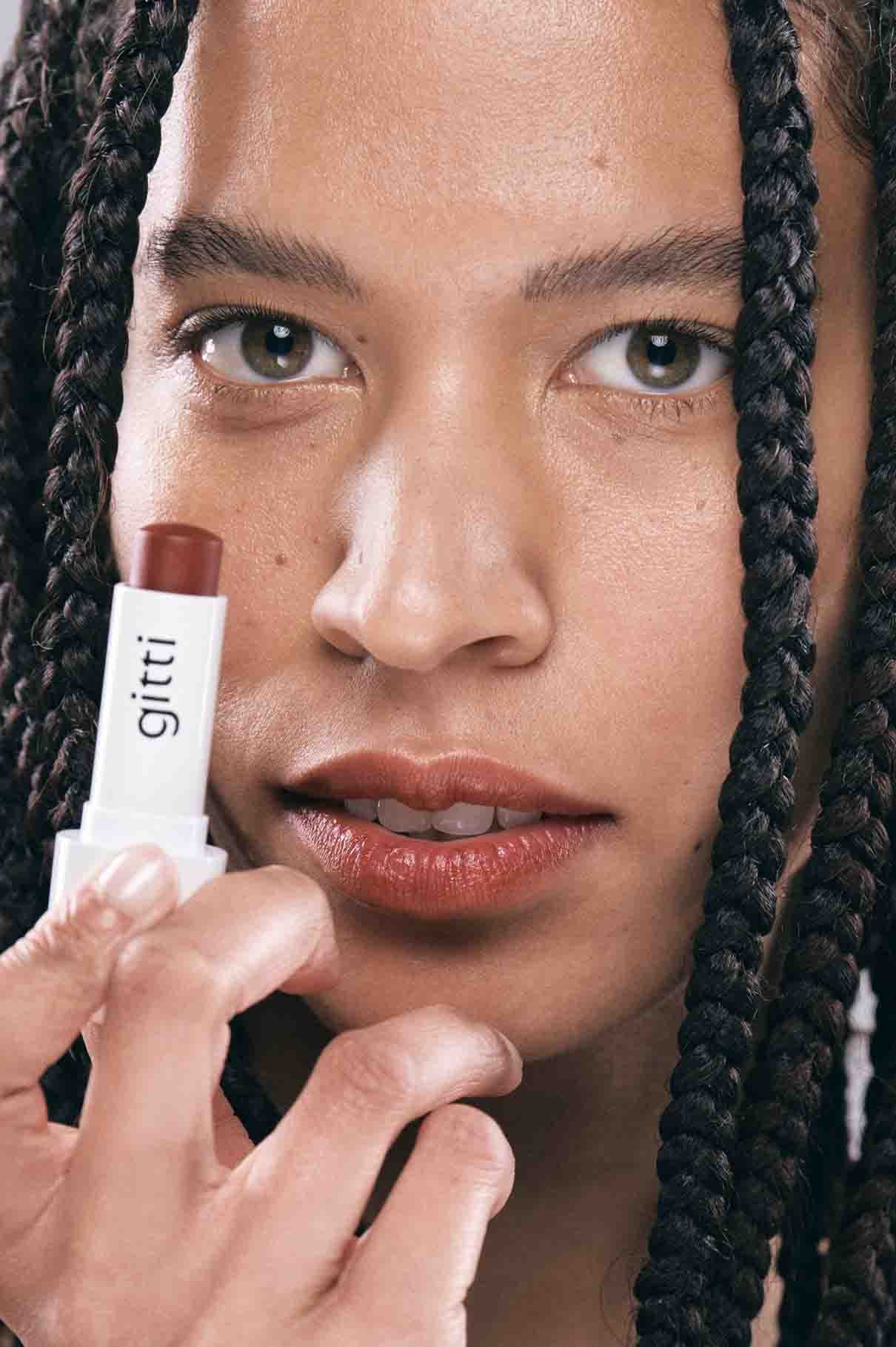 Eine Nahaufnahme zeigt eine Person mit geflochtenem Haar, die Lip Sync Refill no. 01 von gitti in warmem Rot an die Lippen und blickt direkt in die Kamera.