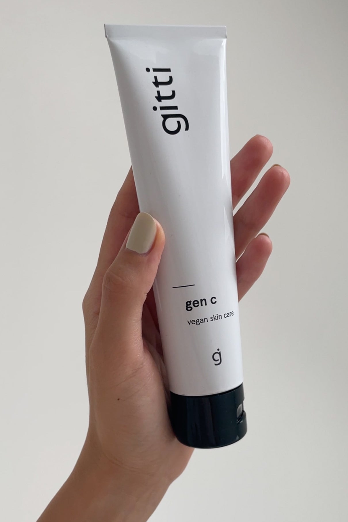 Eine Hand hält eine weiße Tube mit der Aufschrift Essential Routine vegane Hautpflege - ein Essentials-Produkt für Ihre tägliche Schönheitsroutine - vor einem schlichten, hellen Hintergrund.