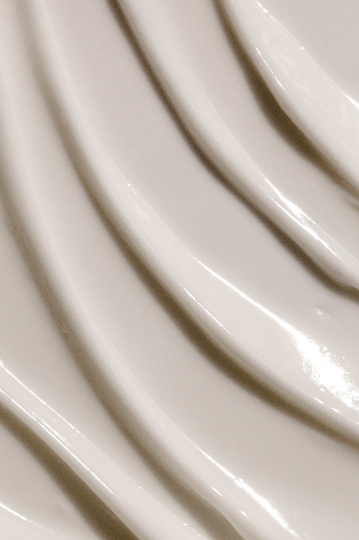 Nahaufnahme von Skin Rhythm Moisturiser Light, einer glatten, glänzenden Creme mit Glow- und Barriereschutz-Zusatz, die in geschwungenen, diagonalen Linien auf einer beigen Fläche verteilt wird.