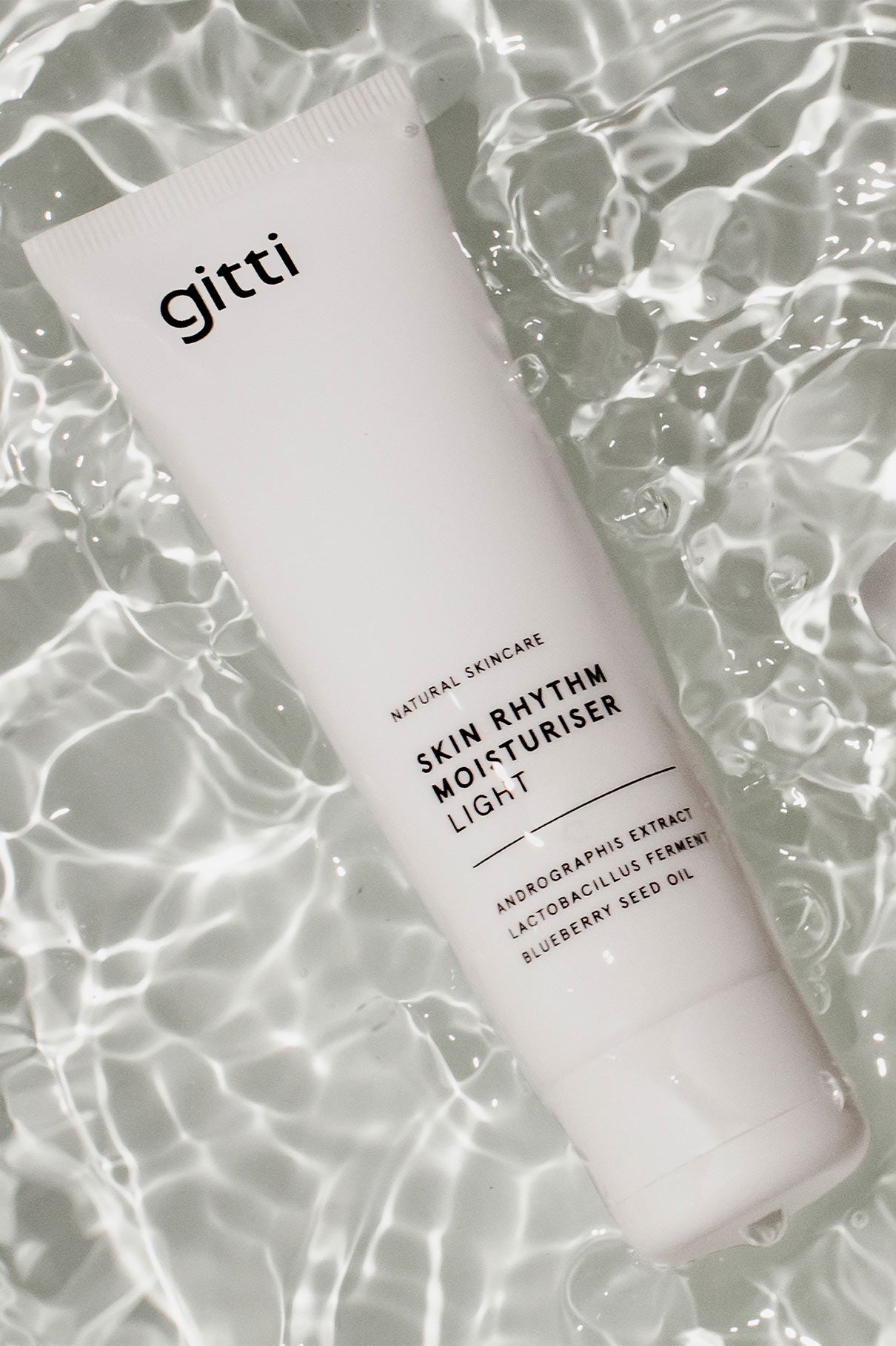 Eine weiße Tube mit der Aufschrift Skin Rhythm Moisturiser Light ruht auf plätscherndem Wasser und spiegelt das Versprechen von Feuchtigkeit und einem gesunden Glanz für strahlende Haut wider.