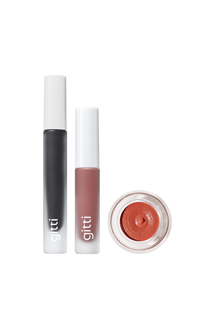 Das Lash, Lip & Cheek Trio - mit Mascara in einer schwarzen Tube, Lip Glaze in einer rosa-braunen Tube und rot schimmernder Velvet Cheeks Creme in einem kleinen Tiegel - wird auf einem weißen Hintergrund präsentiert.