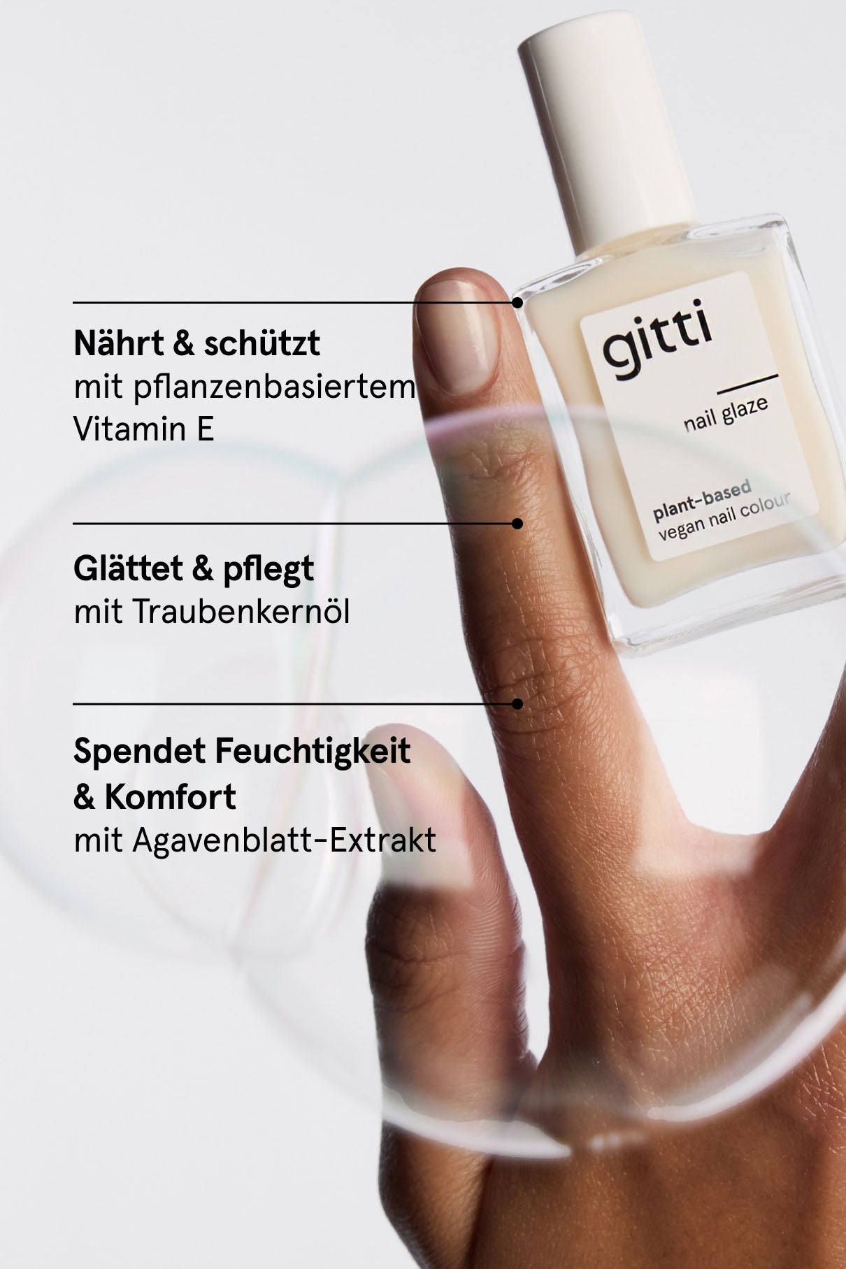Eine Hand hält eine Flasche Nail Glaze Mylk, während drei Textabschnitte die Vorteile hervorheben: nährt mit Vitamin E, glättet mit Traubenkernöl und spendet Feuchtigkeit mit Agavenblattextrakt für einen atemberaubenden Glasnagel-Look.
