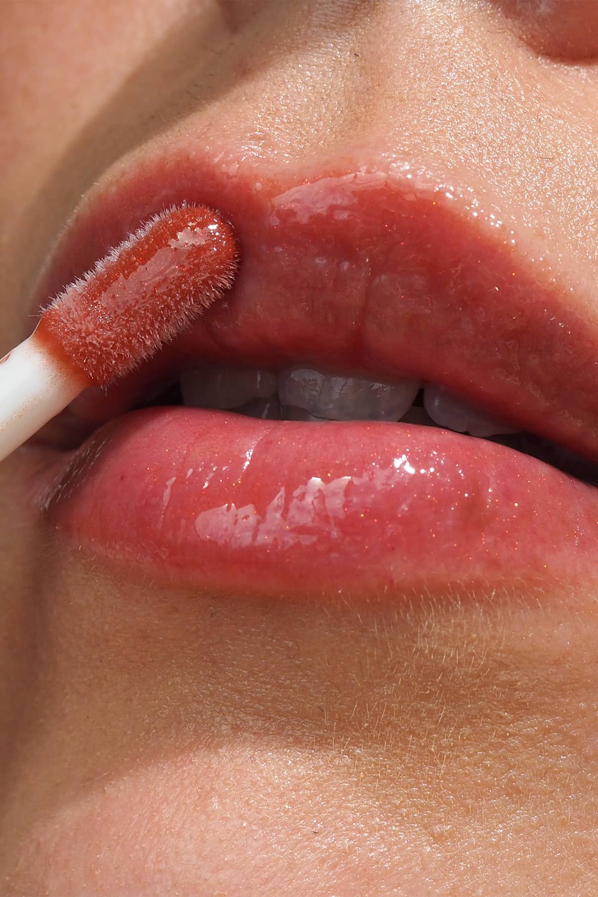 Nahaufnahme einer Person, die Lip Glaze no. 04 mit einem Applikator auf die Lippen auftragen, um ein hochglänzendes Finish zu erzielen.