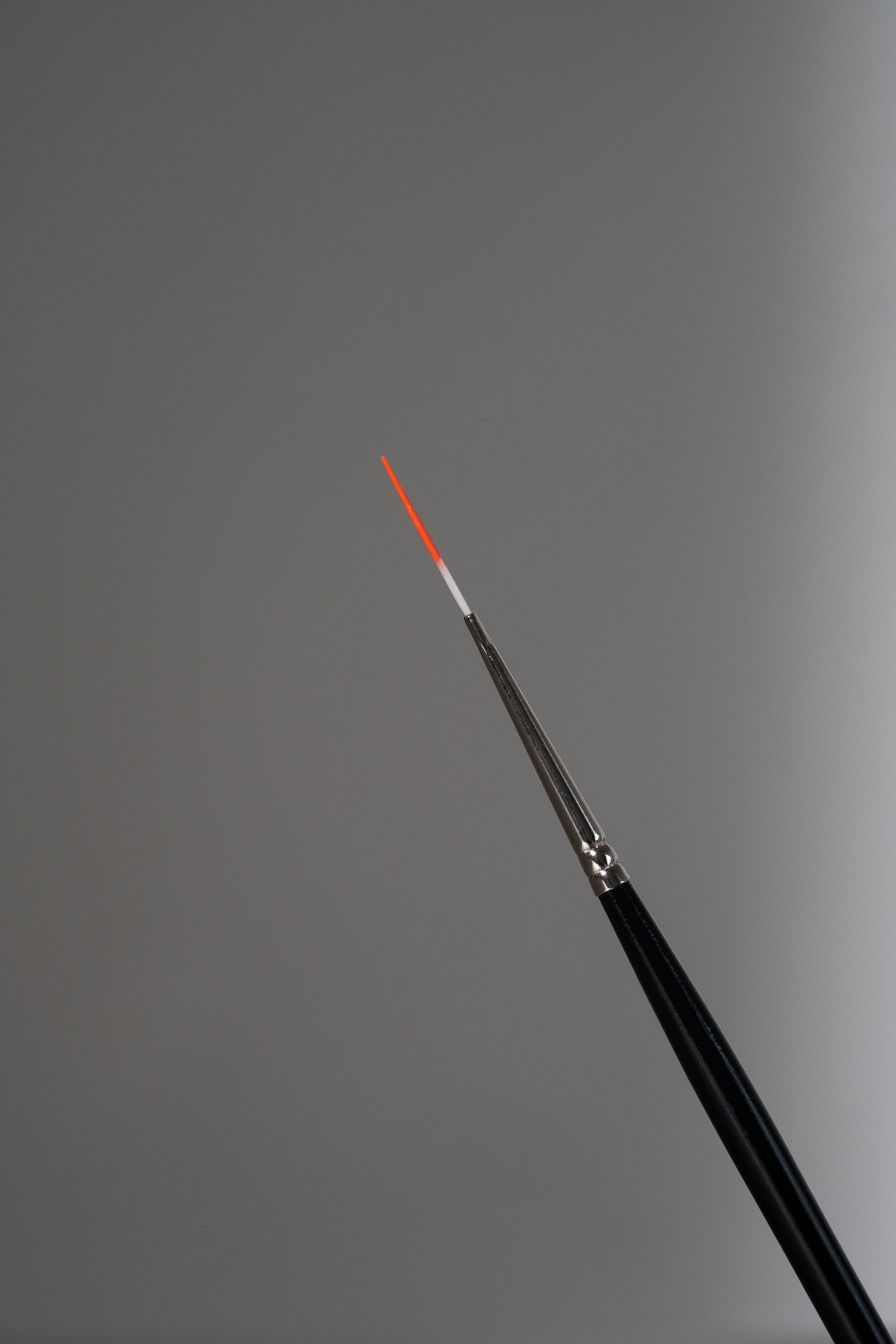 Das Nail Art Duo besteht aus einem dünnen Pinsel mit einer feinen Spitze, die in orangefarbene Farbe getaucht ist und auf einem schlichten grauen Hintergrund steht - ideal für detaillierte Designs oder in Kombination mit dem mitgelieferten Dotter für kreative Nail Art.