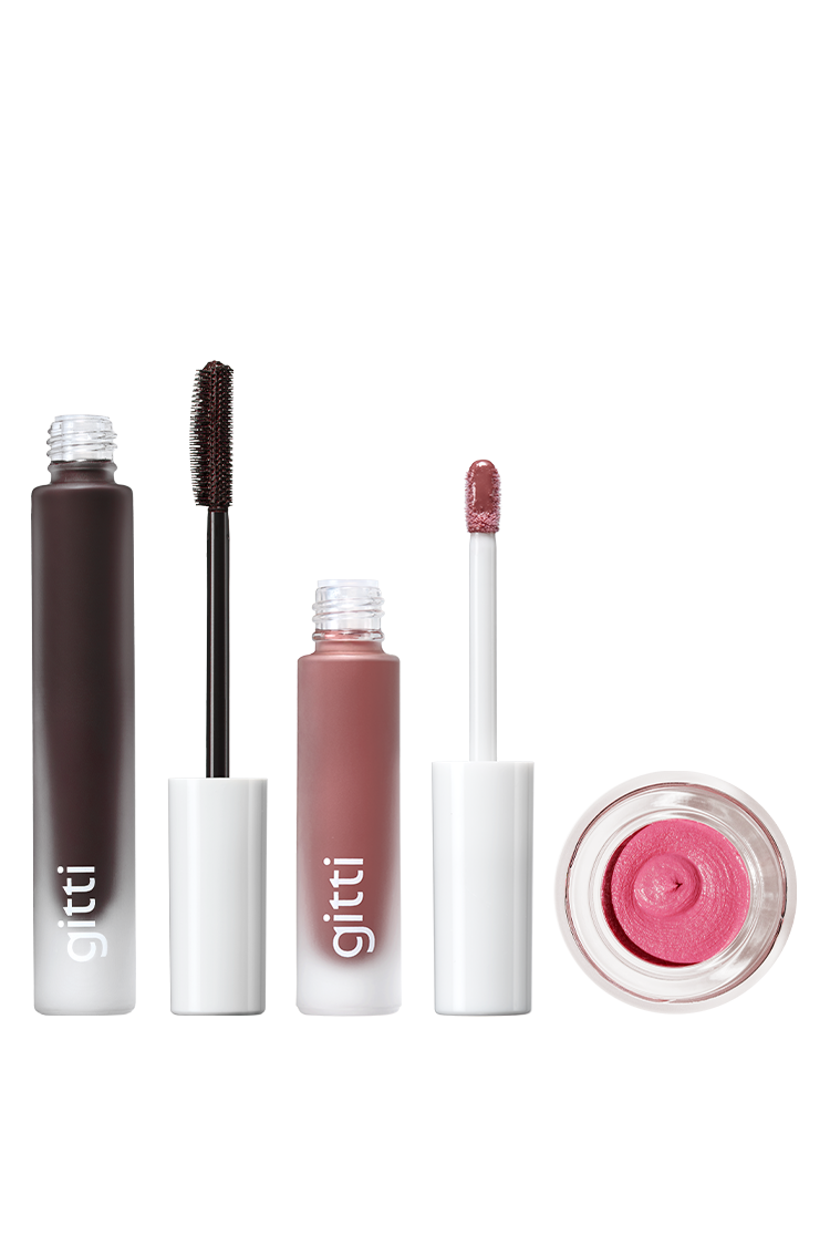 Das gritti Lash, Lip & Cheek Trio ist in einer Reihe ausgestellt: ein Mascara, Lip Glaze und ein offener Velvet Cheeks Creme-Rouge-Tiegel, jeweils mit einer weißen Kappe.