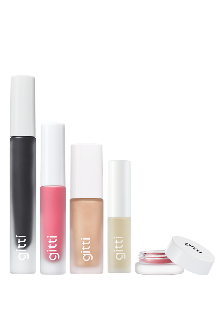 Das Gitti Signature Set enthält fünf Kosmetikprodukte in einer Reihe: eine schwarze Tube Mascara, rosa Velvet Cheeks, einen beigen Flakon, einen klaren Flakon und einen offenen kleinen runden Behälter mit weißem Deckel.