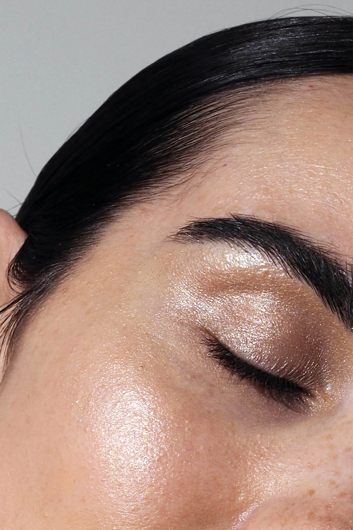 Close up of an eye with shimmering champagne eyeshadow and neatly groomed brow